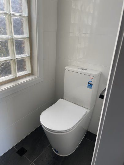 White Toilet is Sitting in a Bathroom Next to a Window — Happy Housekeepers in South Tamworth, NSW