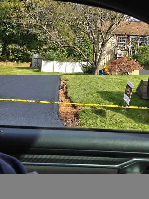 Driveway and lawn outside a house, with yellow caution tape across the foreground.