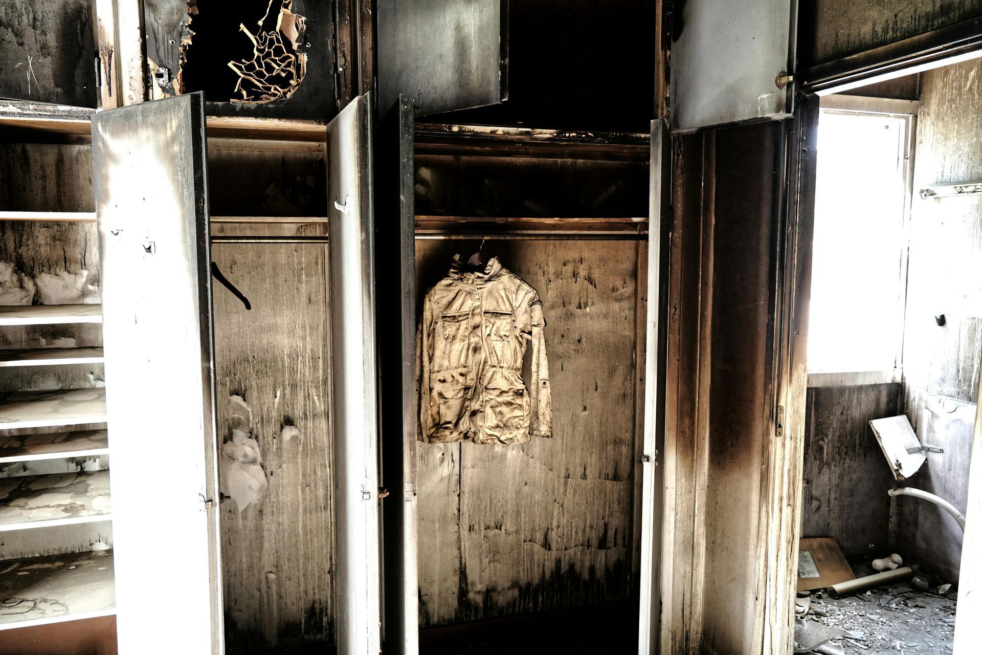 A dirty closet with a jacket hanging on the door