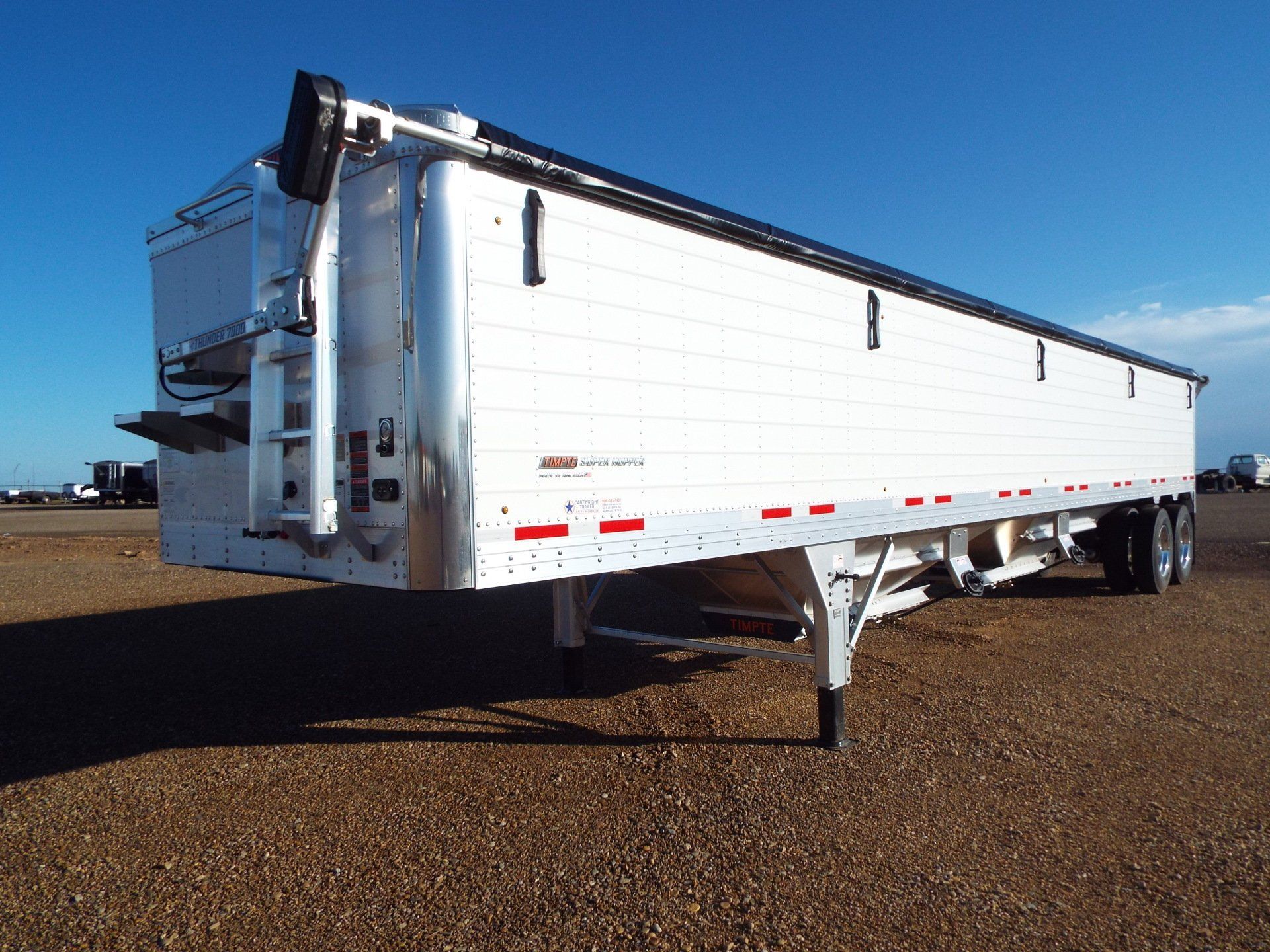 White grain hopper trailer parked outdoors.