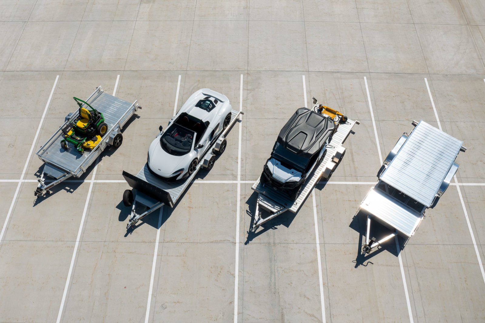 A group of cars and trailers are parked in a parking lot.