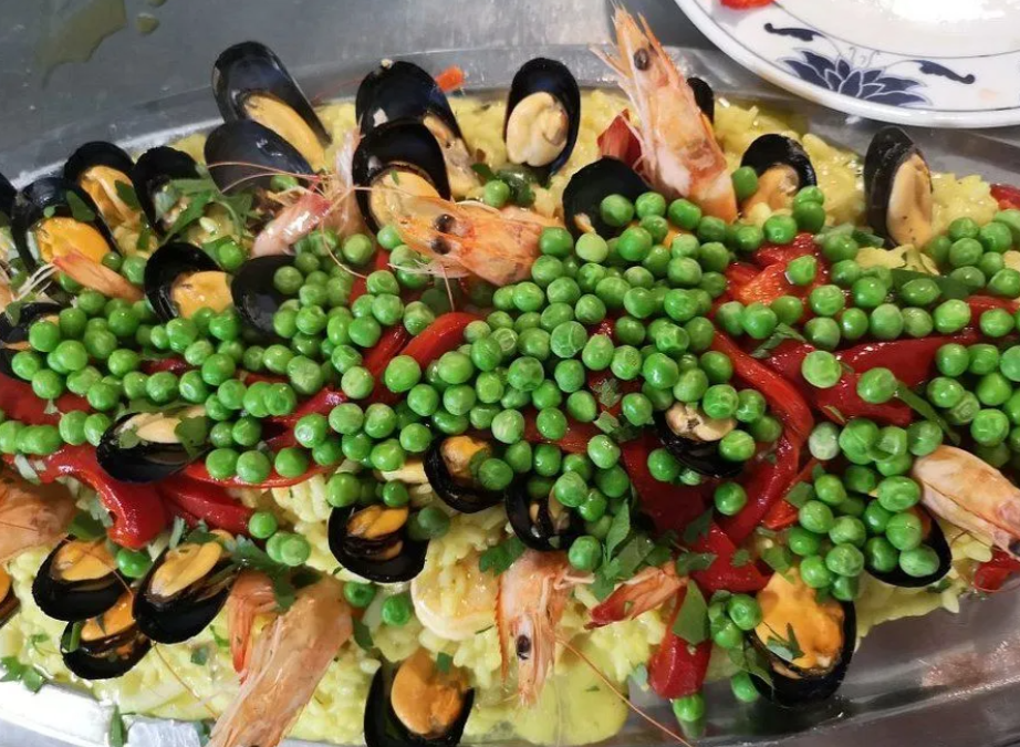 Piatto di frutti di mare con piselli, cozze, gamberi e strisce di peperone rosso.