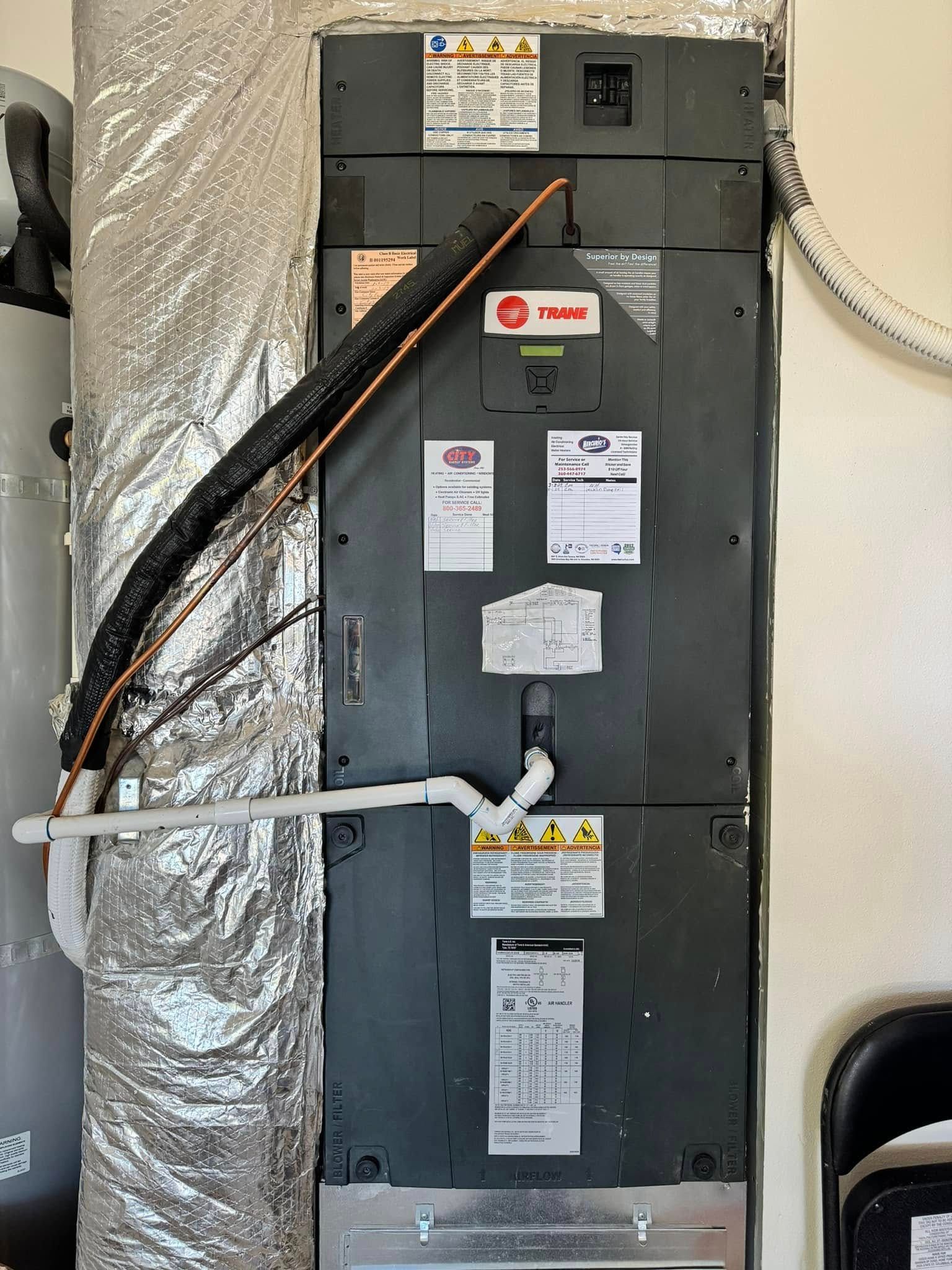 Residential HVAC furnace with foil-wrapped ductwork and gas line in a utility closet