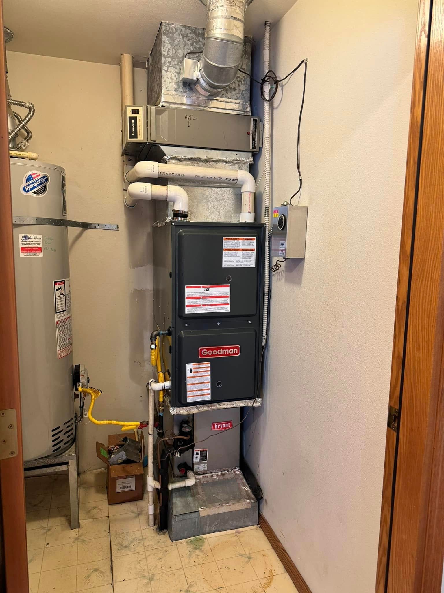 HVAC furnace and ductwork in a narrow utility closet with a gas line and electrical panel