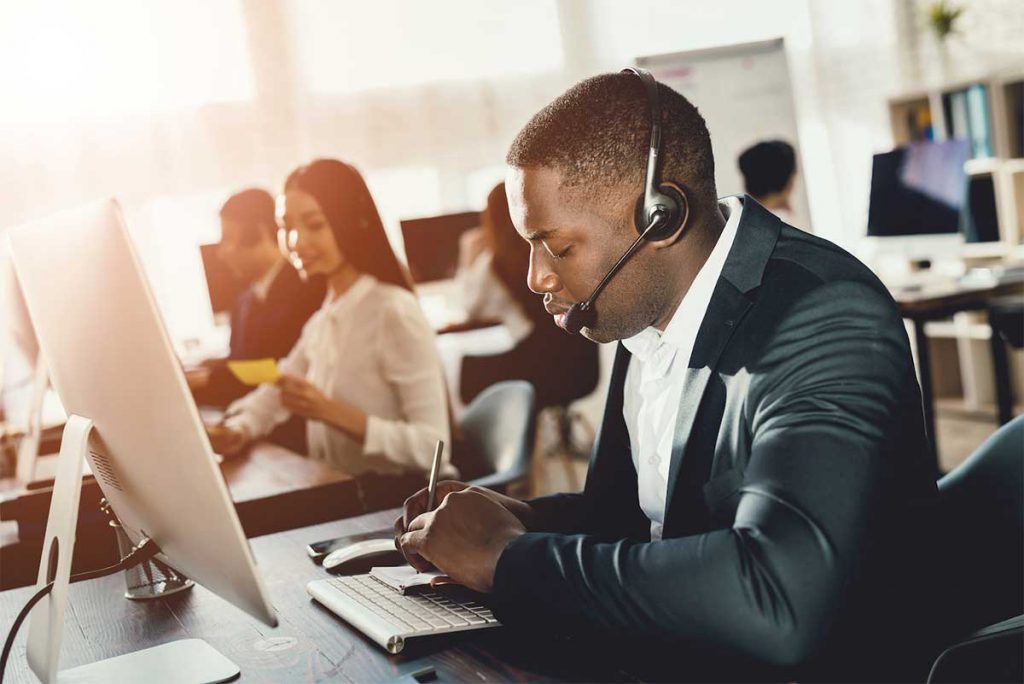 Un homme portant un casque est assis à un bureau devant un ordinateur.