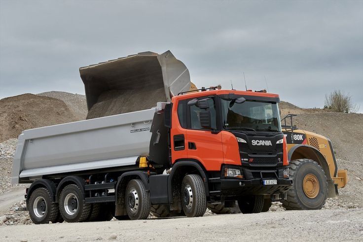 Un camion-benne est garé à côté d'un bulldozer dans un champ de terre.