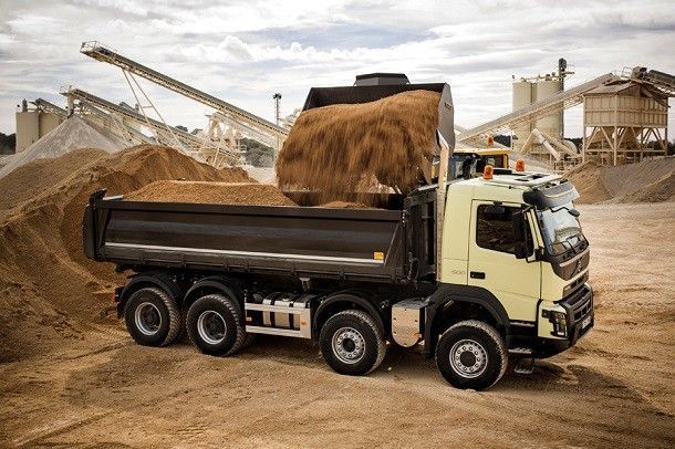 Un camion-benne est chargé de sable dans une carrière.