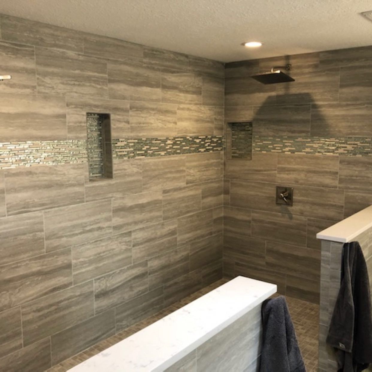 A bathroom with a walk in shower and a towel hanging on the wall.