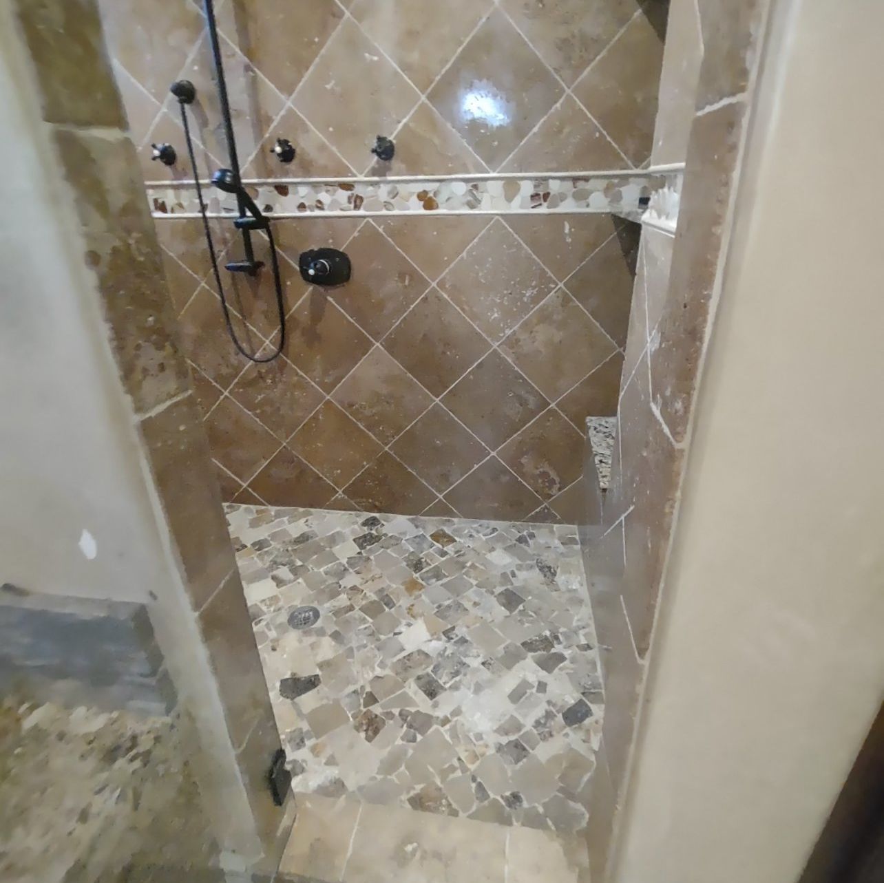 A bathroom with a walk in shower and a tiled floor