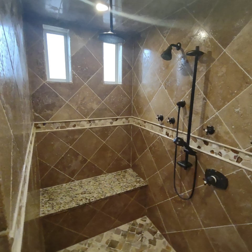 A bathroom with brown tiles and a shower head