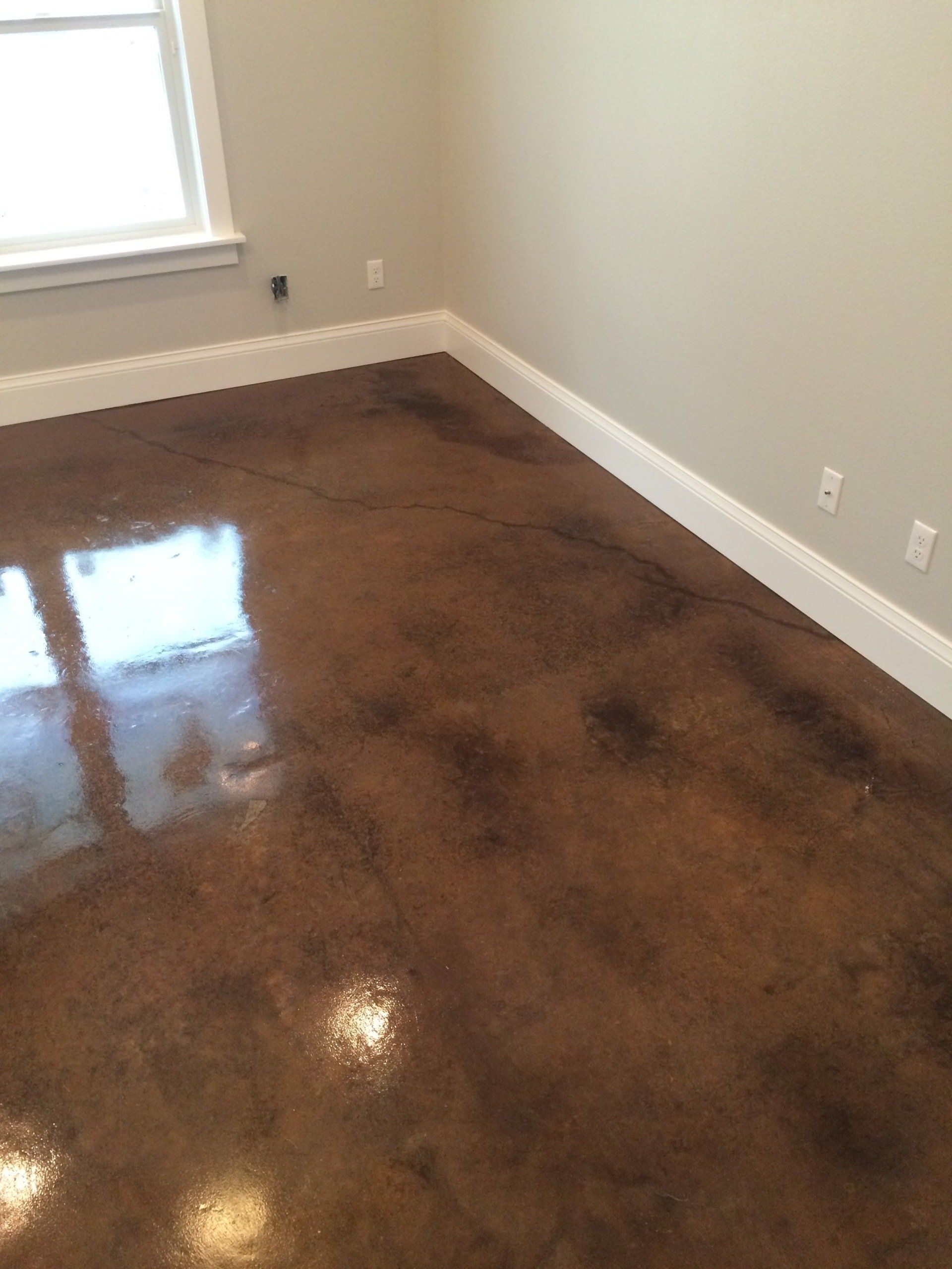 A room with a shiny concrete floor and a window.