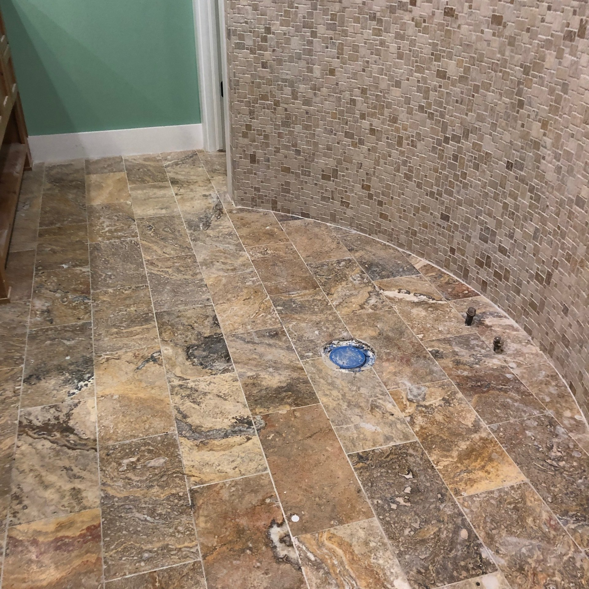 A bathroom with a tiled floor and a blue drain