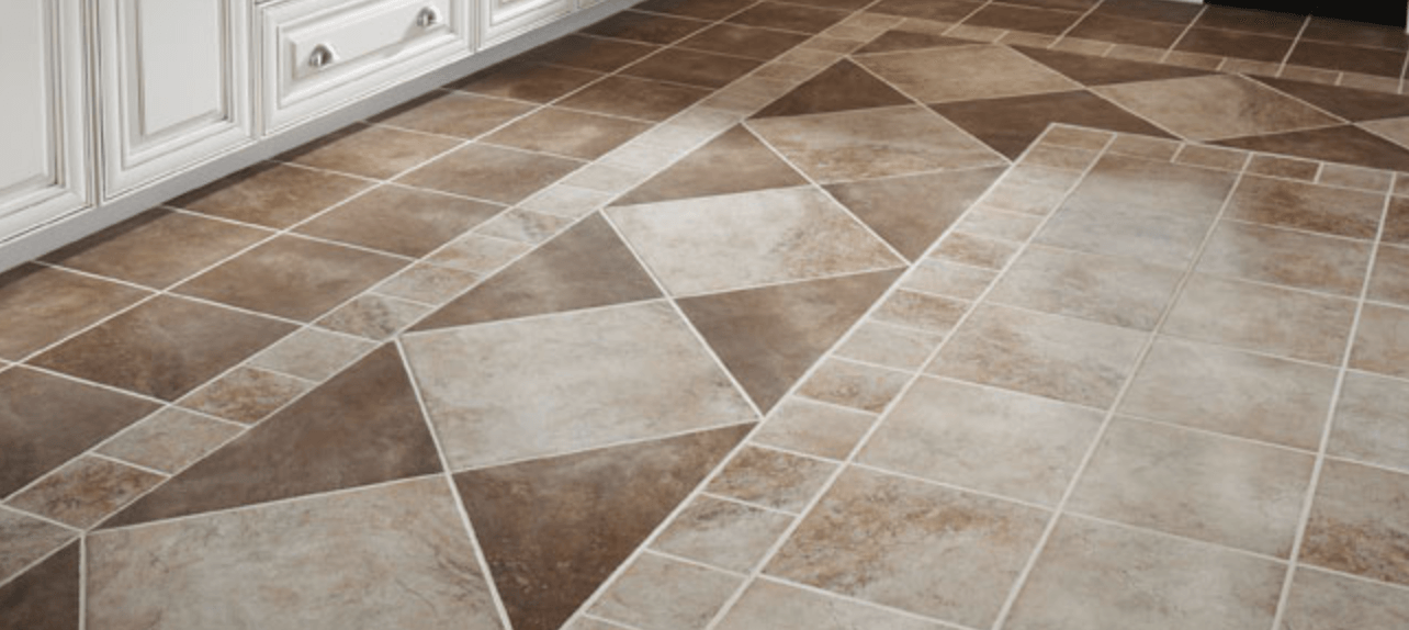 A kitchen floor with brown and white tiles and a checkered pattern.