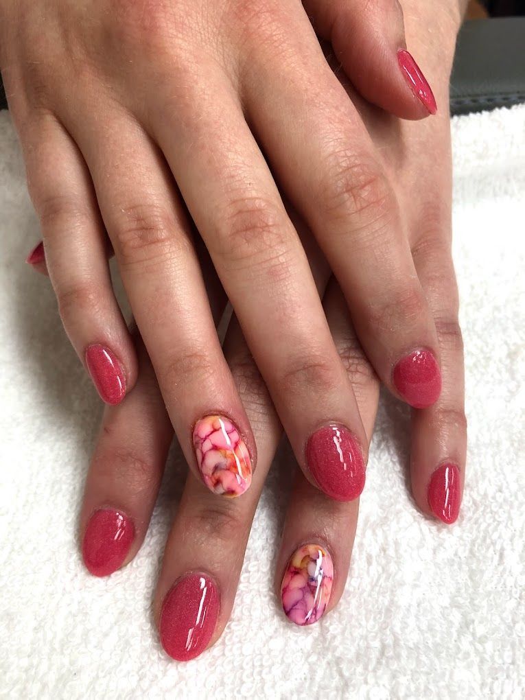 A woman 's nails are painted pink and have a floral design on them.