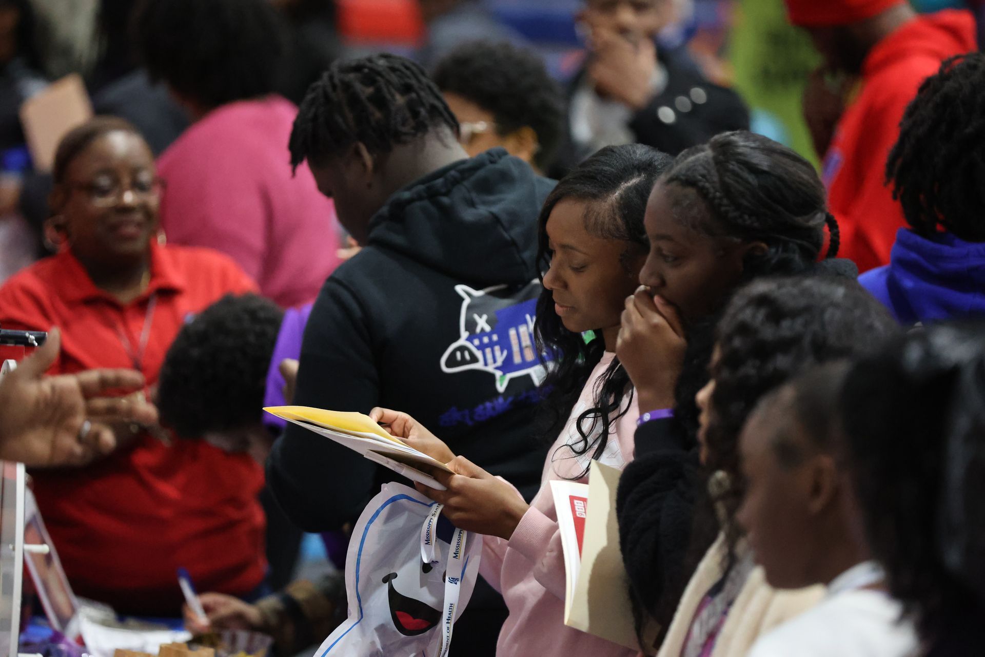 People looking at documents at an event. Some are wearing purple and black, with various expressions.