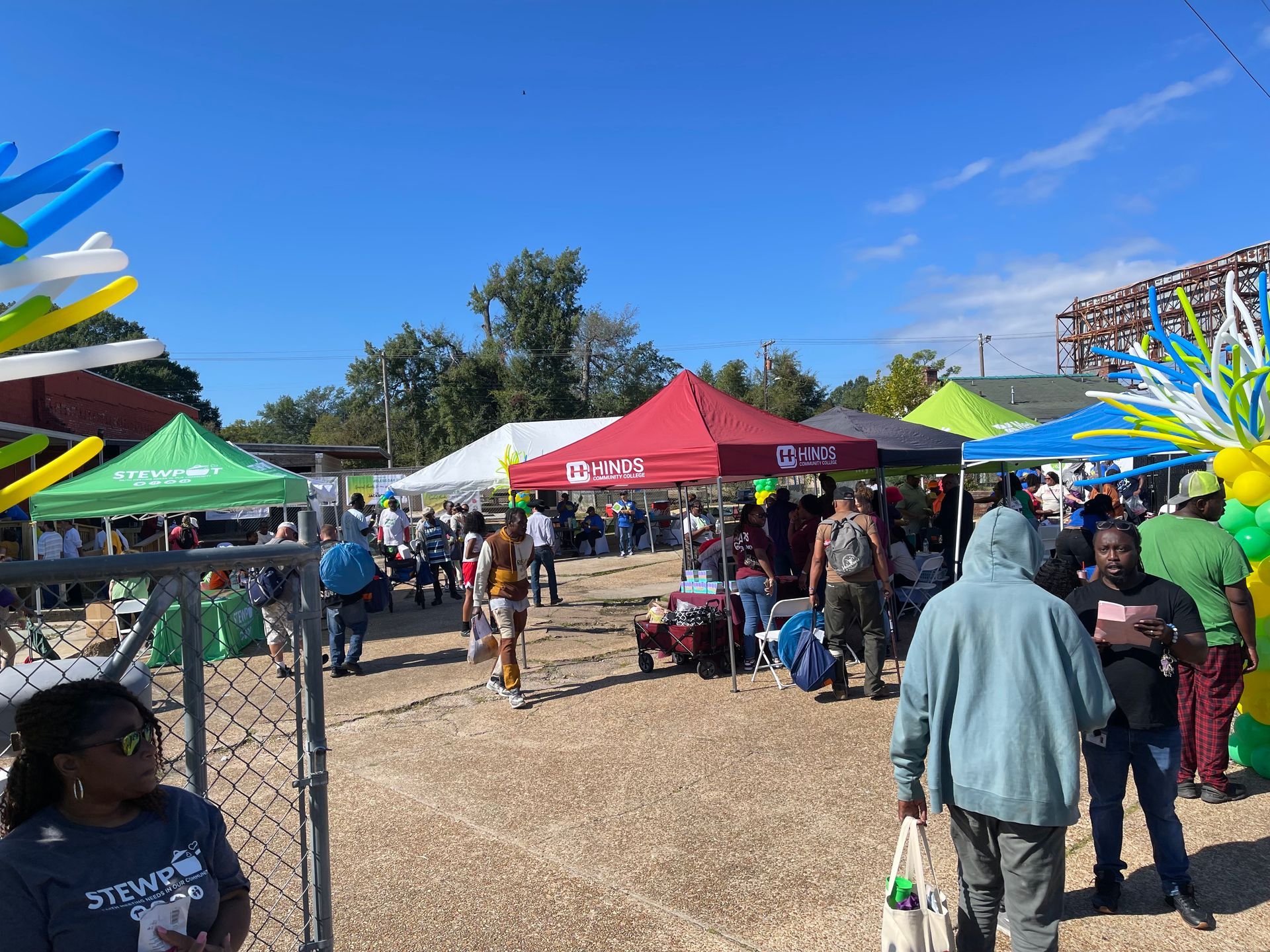 Outdoor event with tents, people, and decorations under a blue sky.