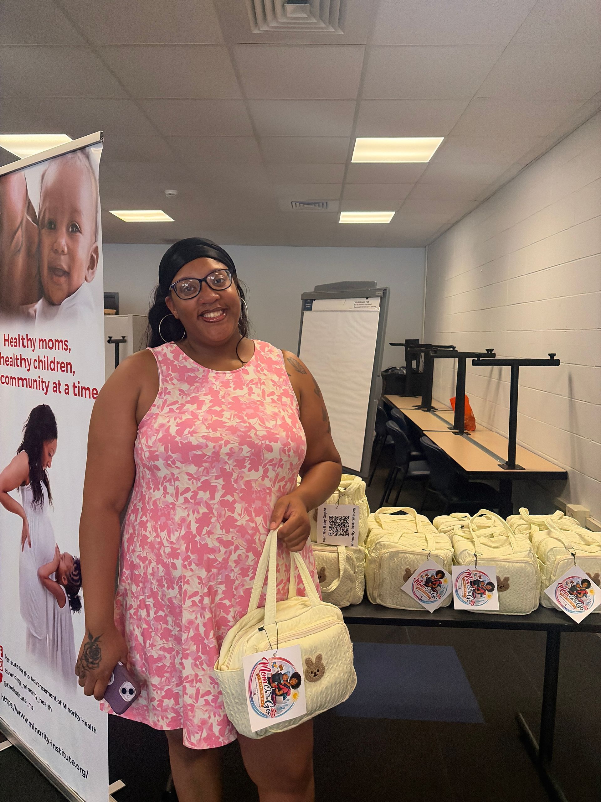 Woman in a pink dress holding a tote bag at a table with wrapped baked goods in a room
