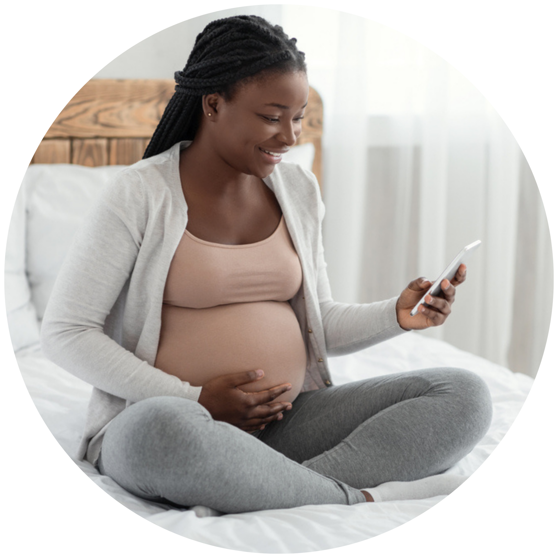 Pregnant person on bed, looking at phone, smiling. Holding stomach. RMOMS