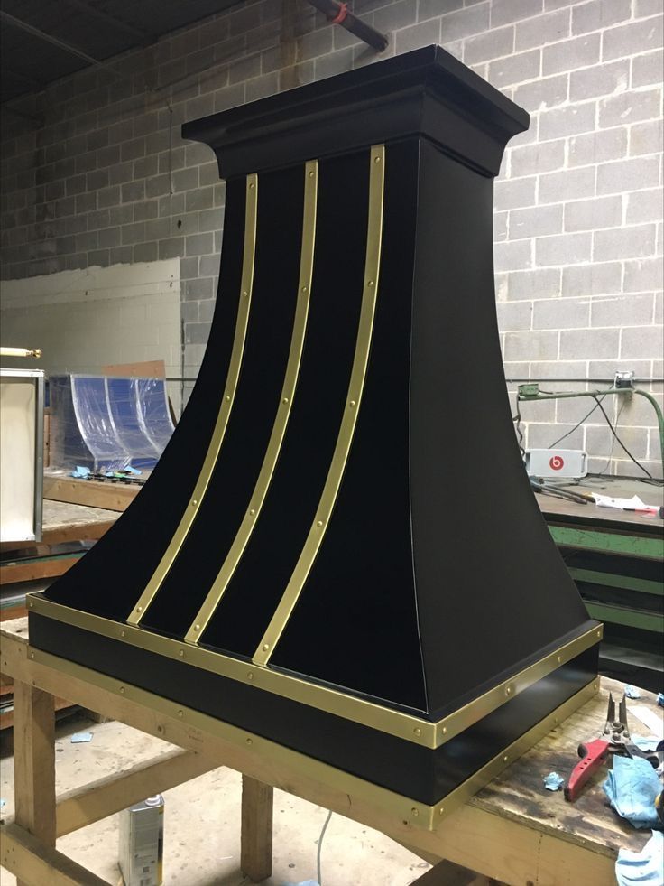 Black decorative mantel or stove hood with gold trim in a workshop on a wooden bench