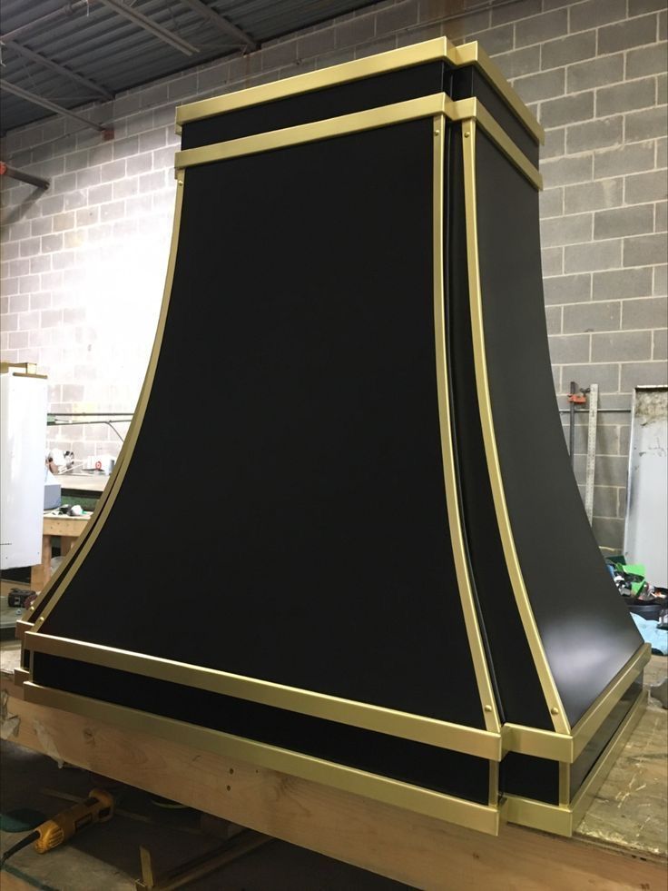 Large black and gold decorative structure in a workshop, mounted on a wooden pallet.