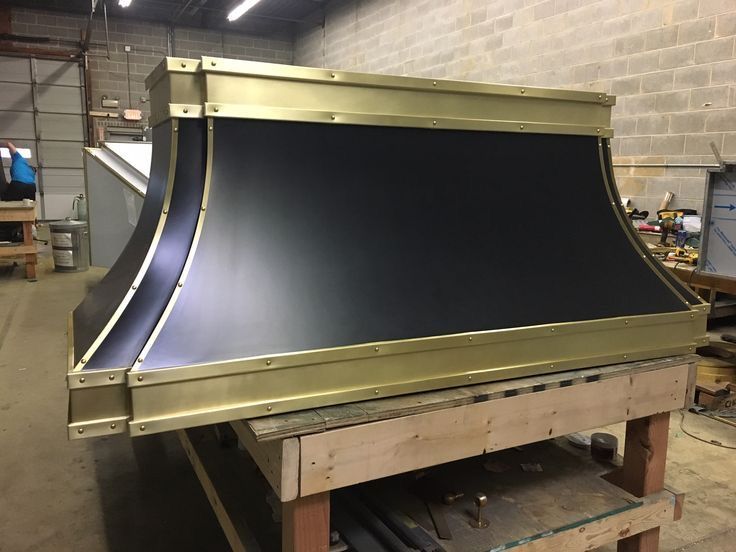 Large black and gold curved metal structure on a wooden workbench in a workshop.