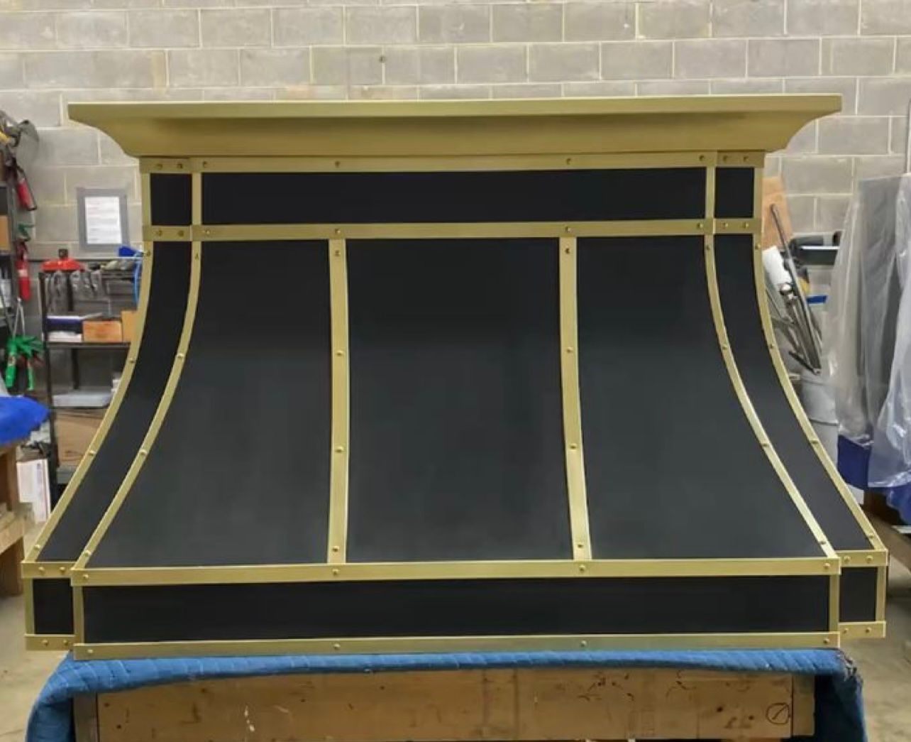 Black-and-gold upholstered display or cabinet front in a workshop, with curved center panels and trim
