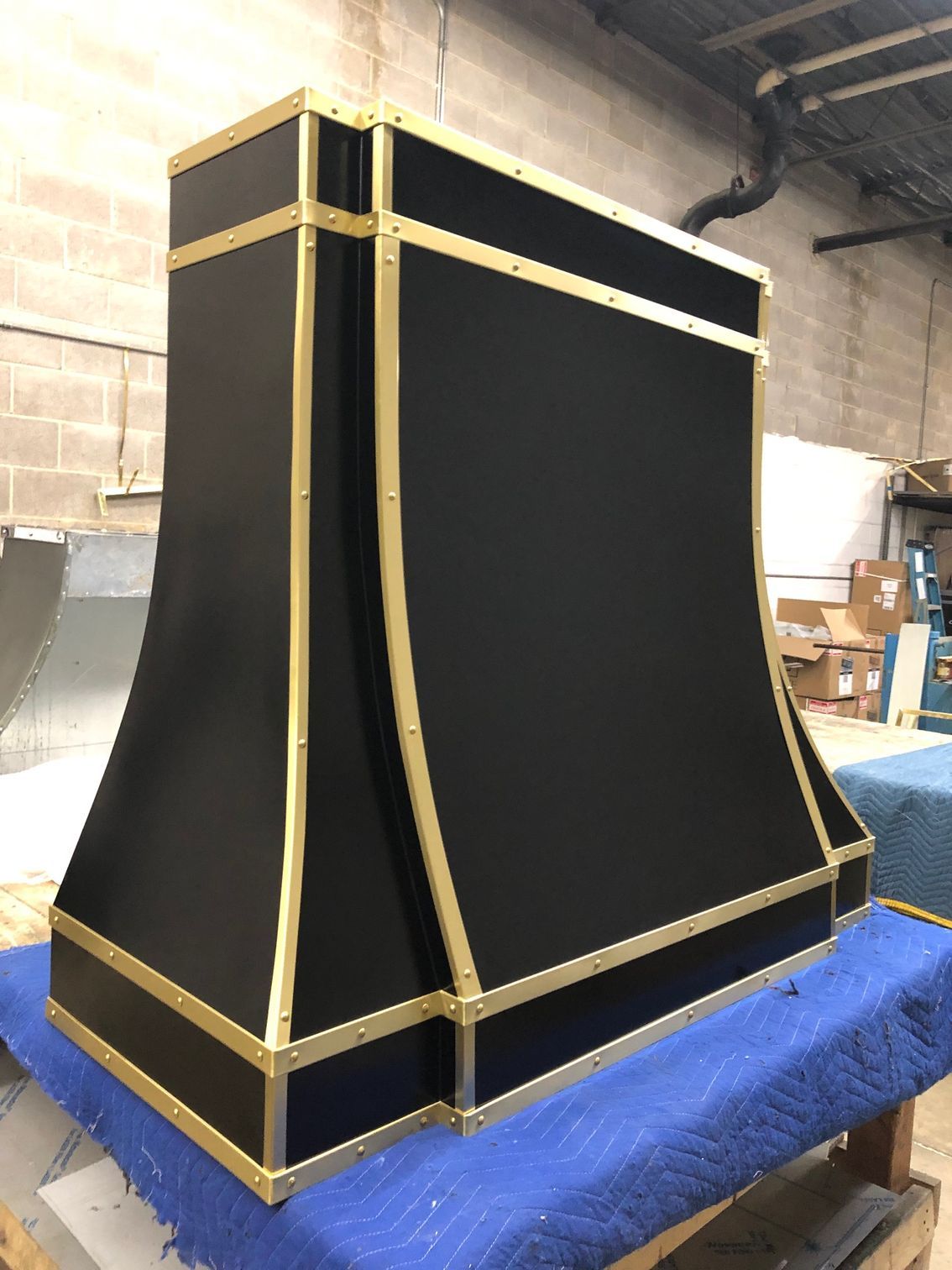 Black-and-gold decorative speaker cabinet on a blue carpet in a workshop garage