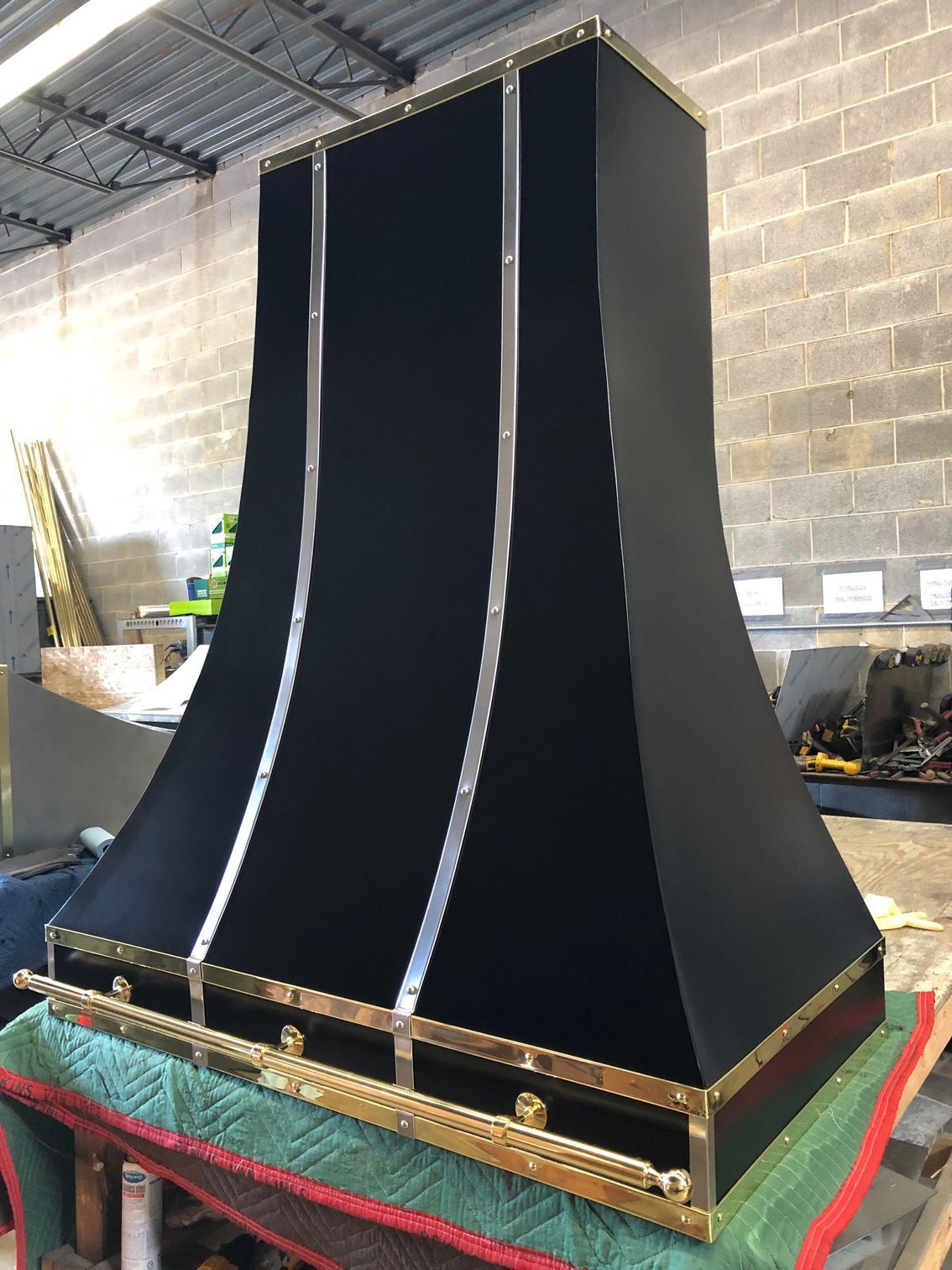 Tall black fabric display with gold trim in an industrial workshop
