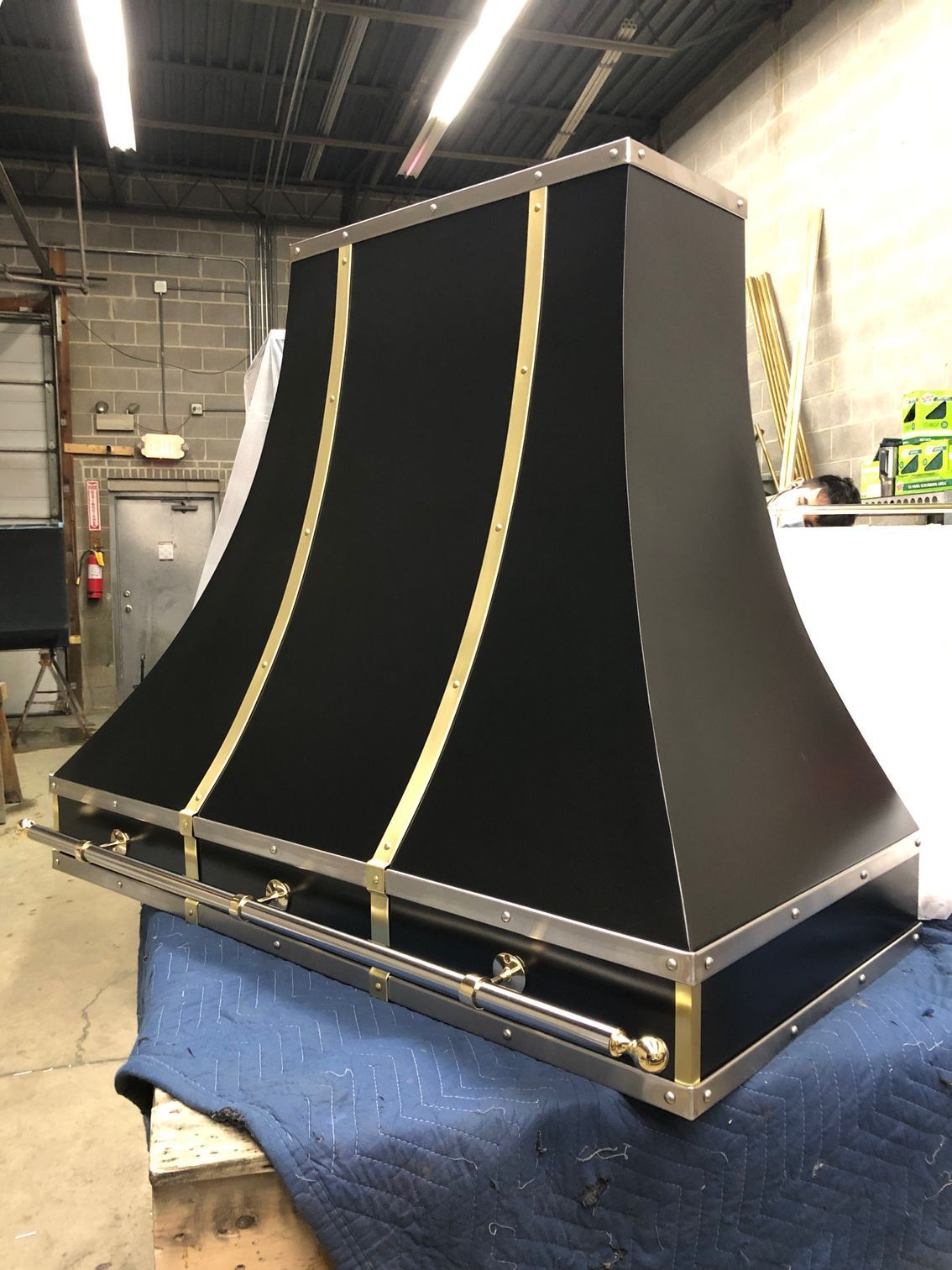 Black fabric-covered stage prop with gold trim in a workshop, sitting on a blue padded table.
