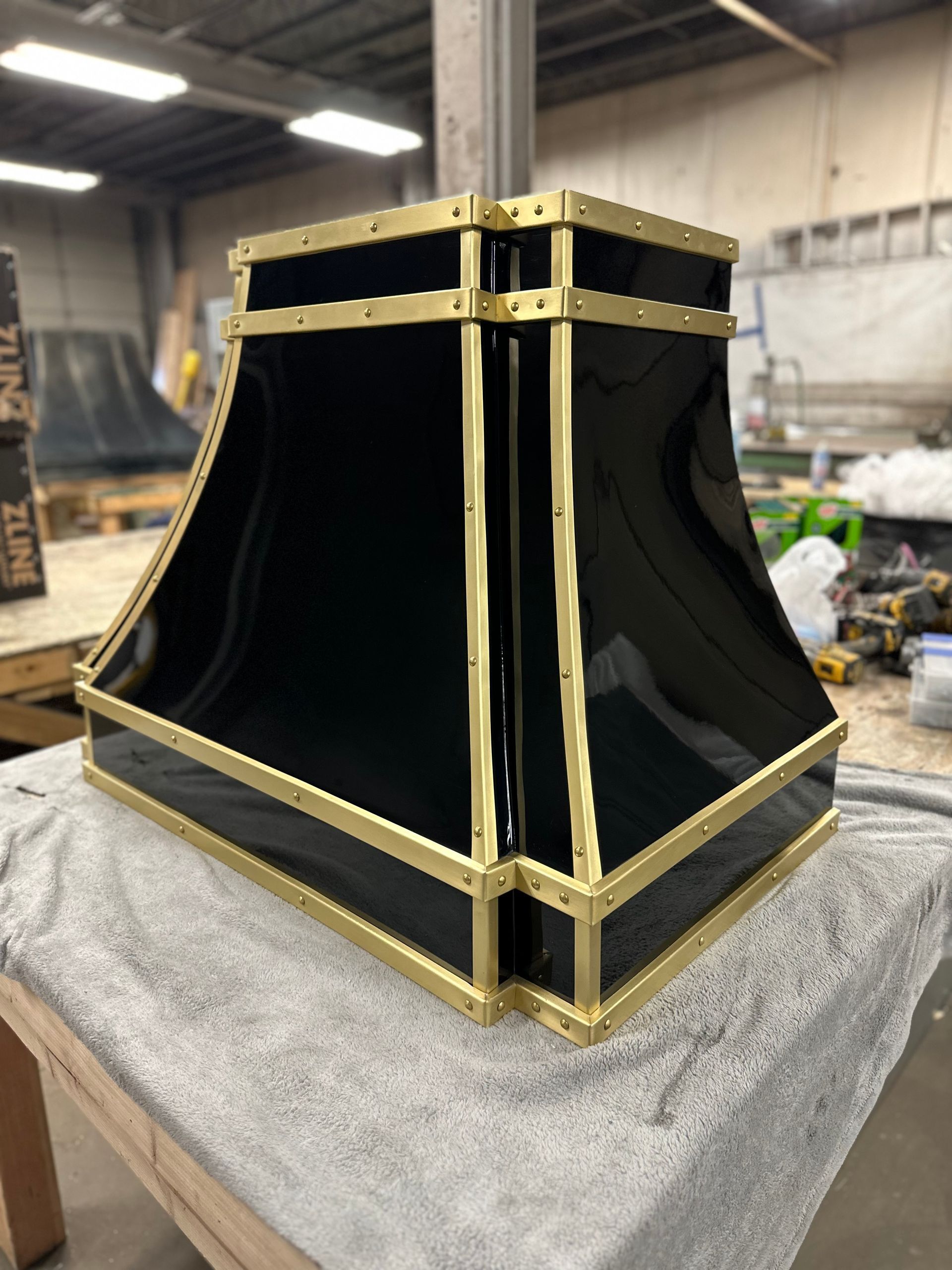 Black and gold decorative metal cabinet or speaker enclosure on a workshop table