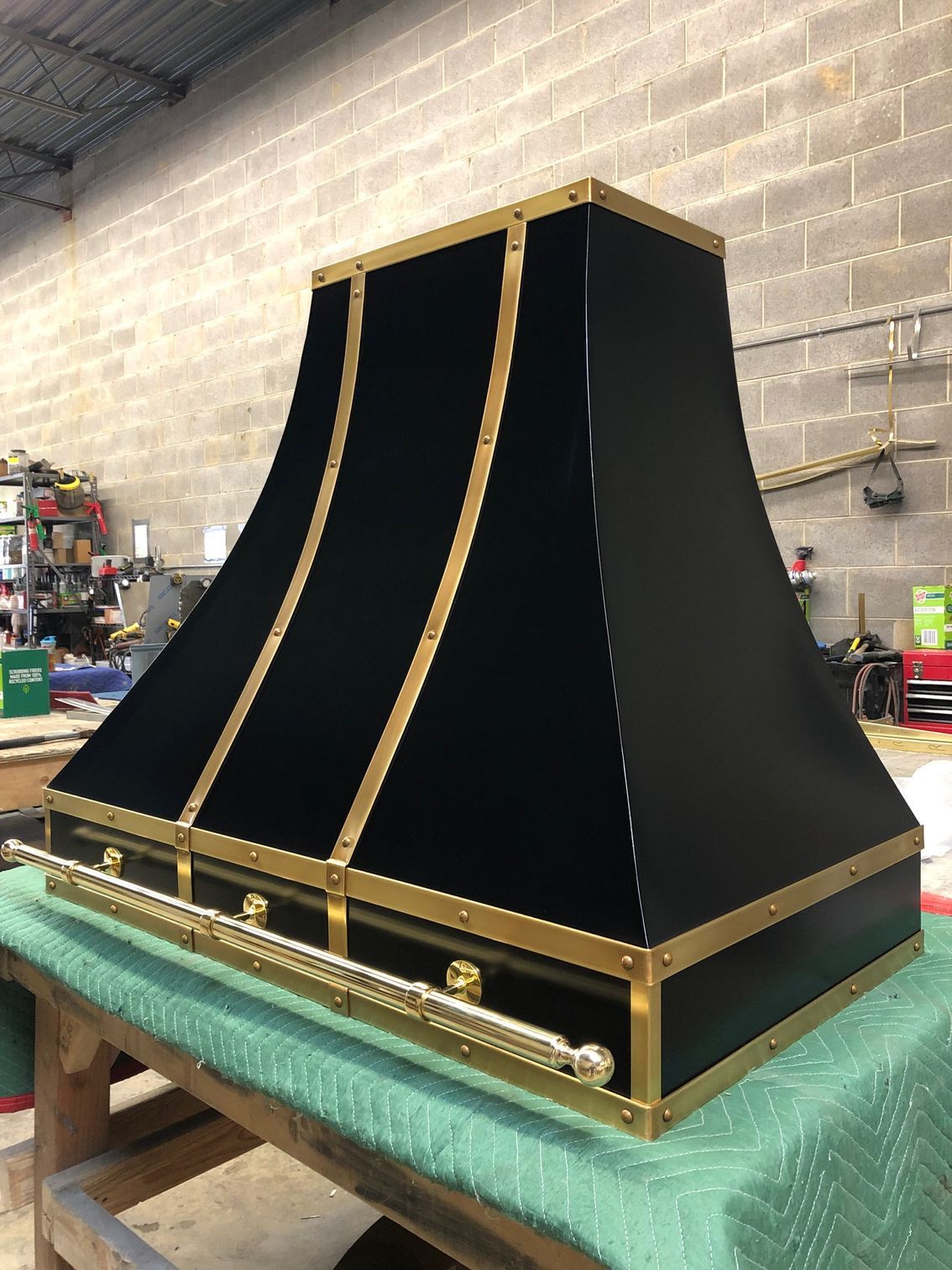 Black-and-gold decorative cabinet or speaker enclosure on a workbench in a workshop