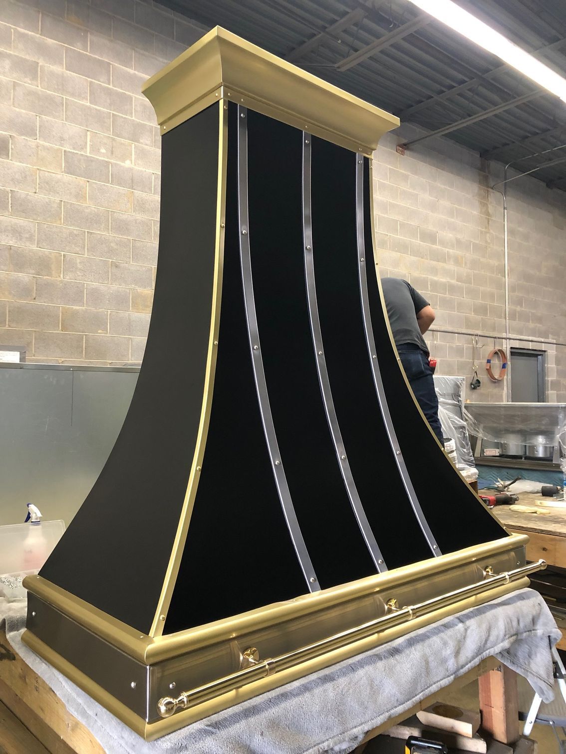 Black-and-gold ornate podium or cabinet on a work table in a workshop, partially covered with cloth