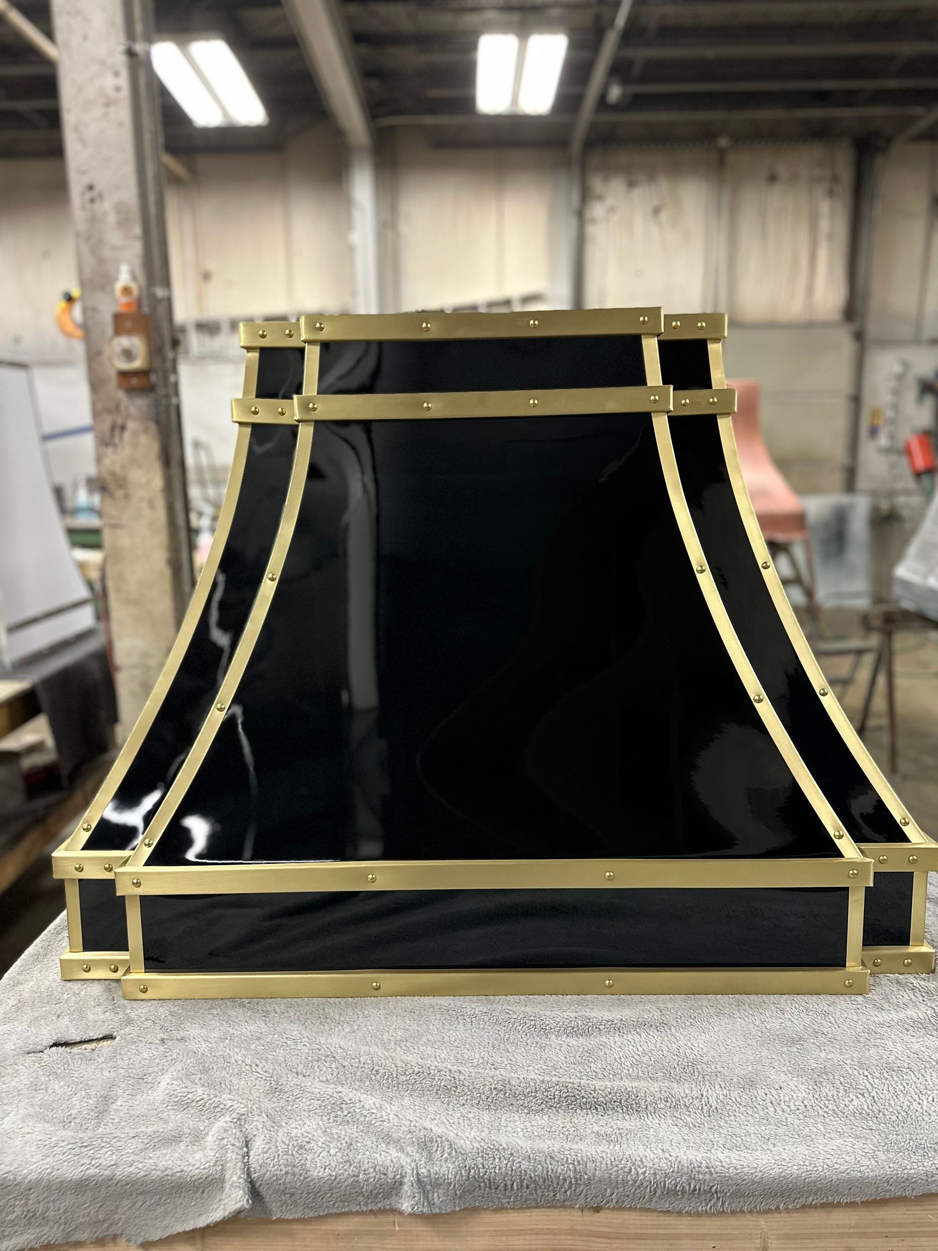 Black industrial duct or chute with gold trim on a workbench in a workshop