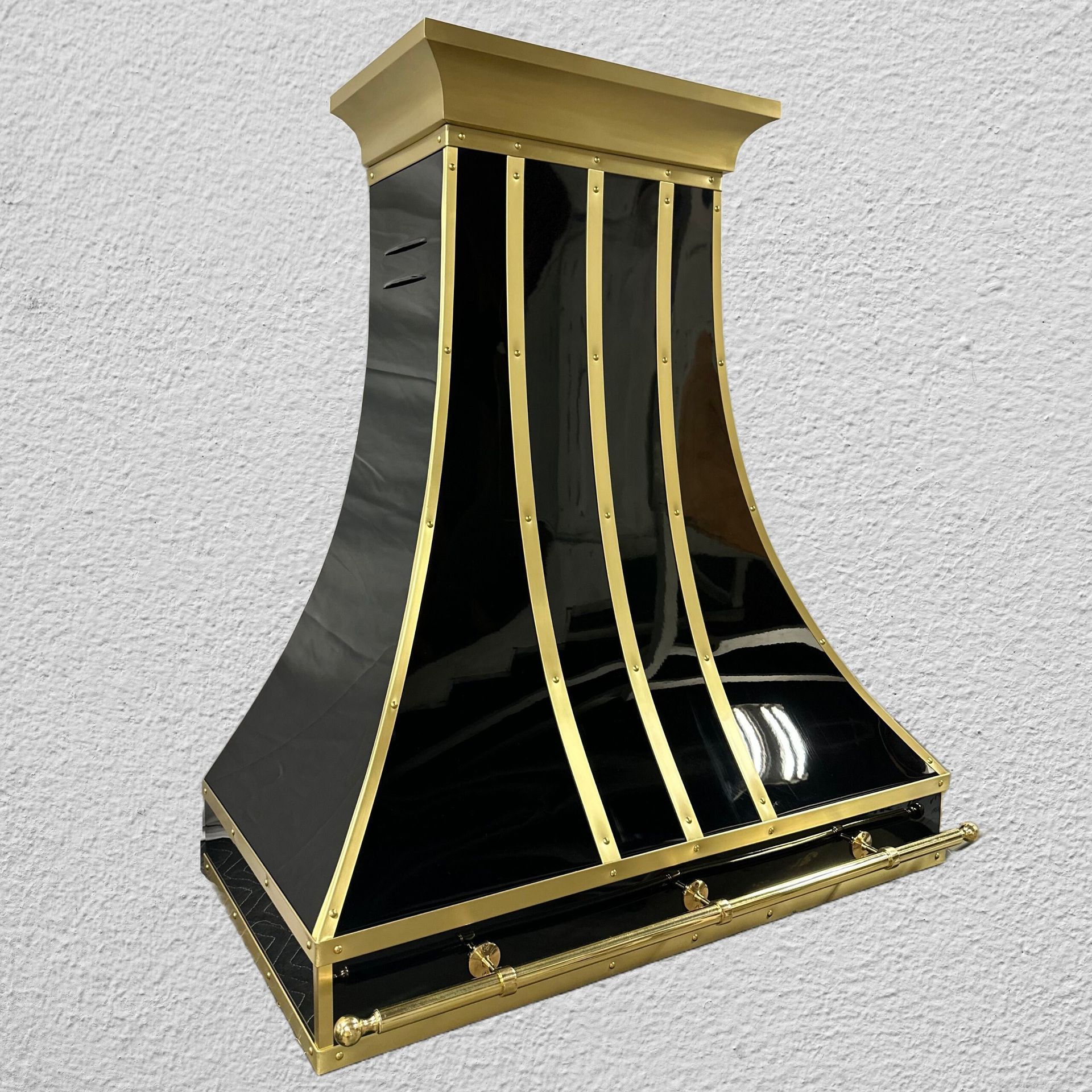 Black and gold modern fireplace hood with curved glass panels on a light wall
