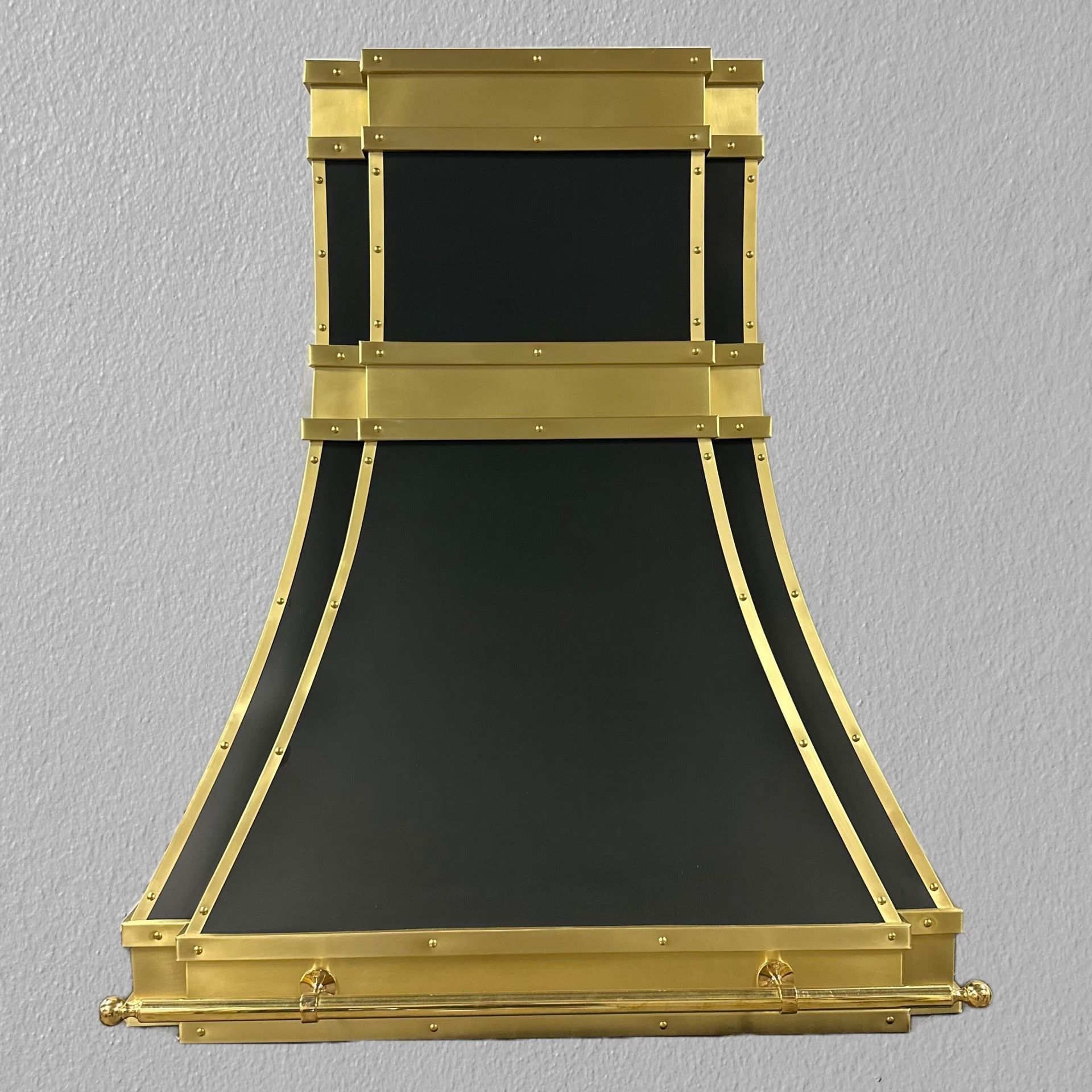 Black and gold folding chair or stool with a curved seat and back on a plain background