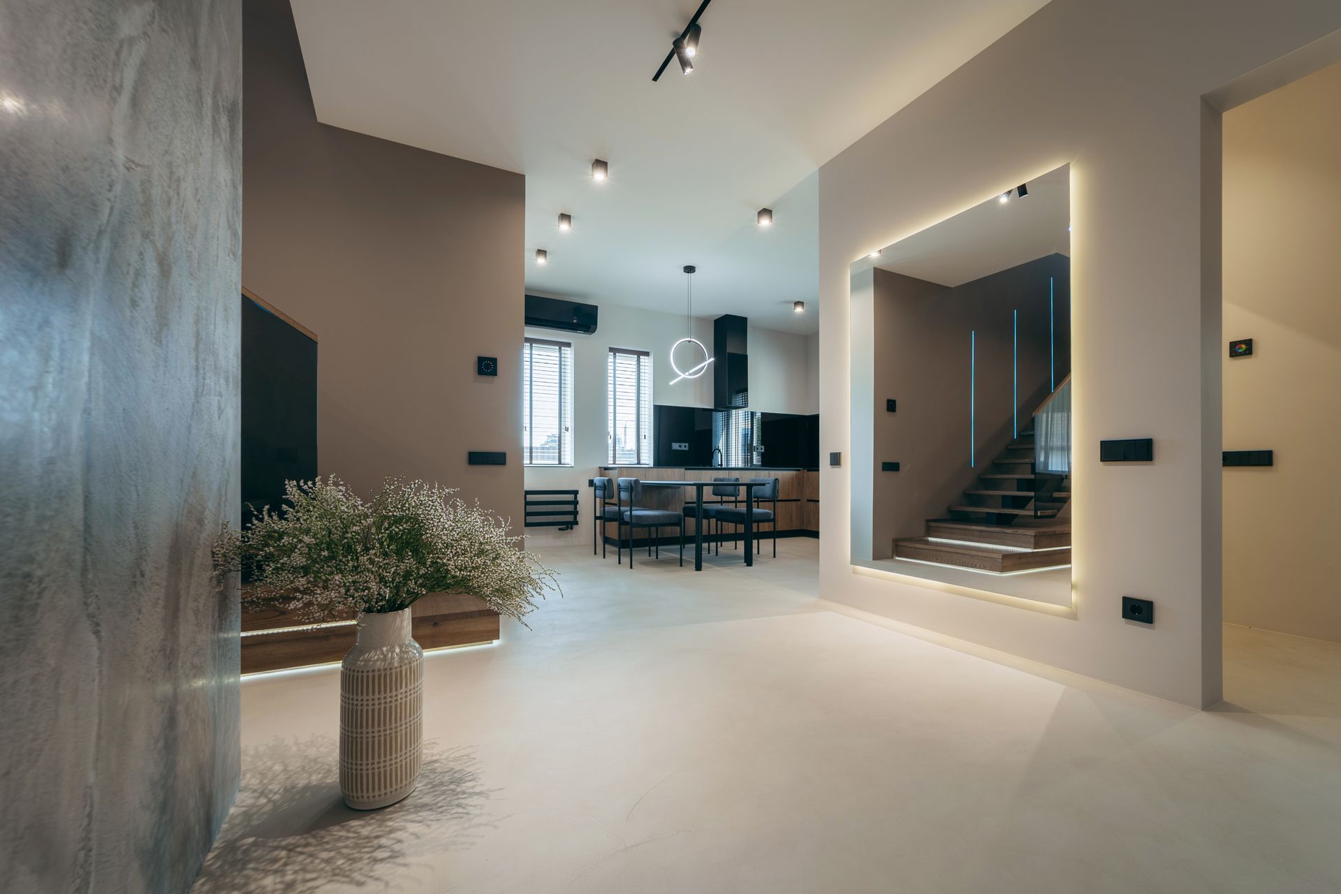 Modern open-plan interior with polished floors, stairs, dining area, and potted plant