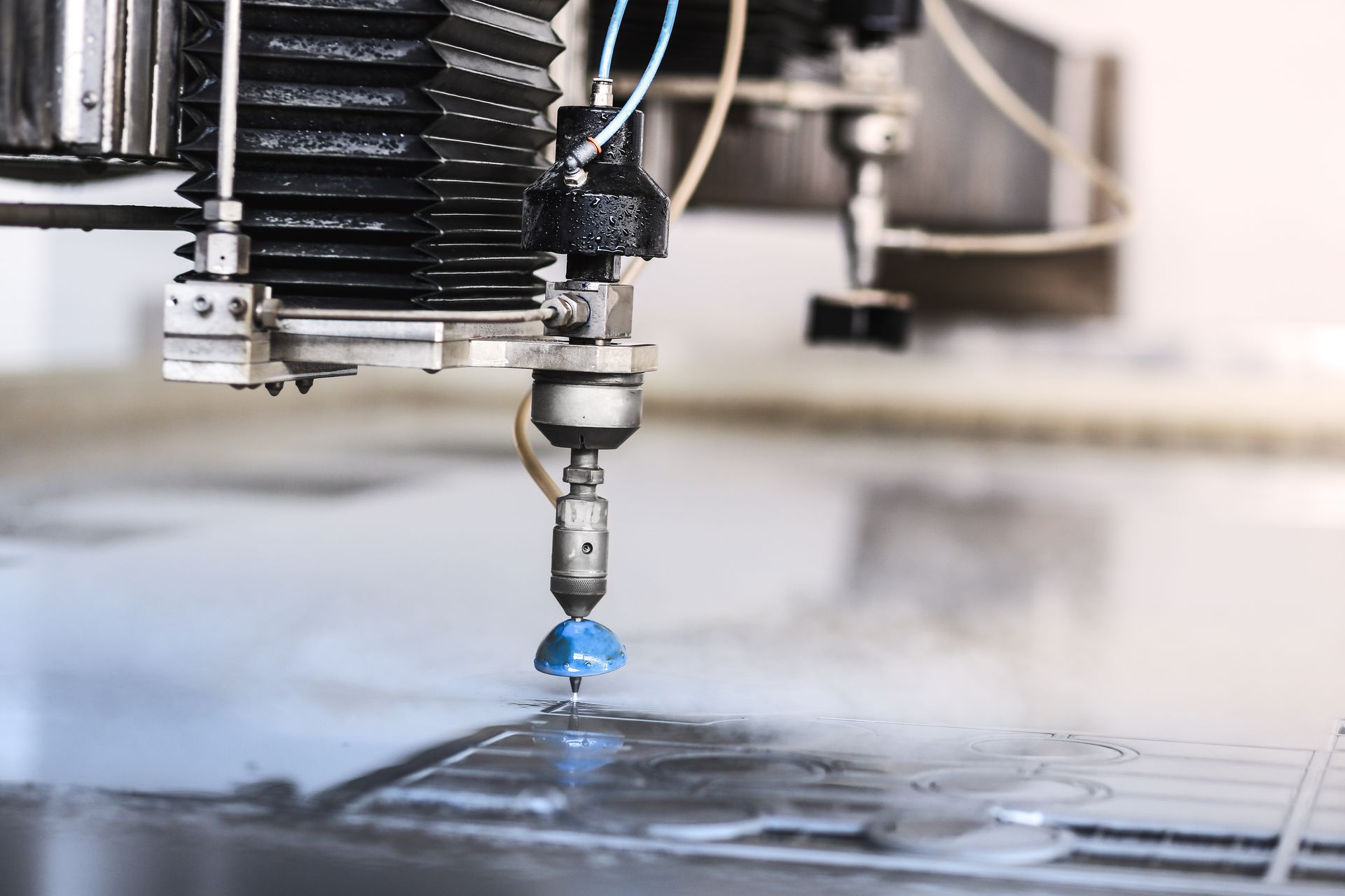 Industrial machine cutting blue material with water on a work surface