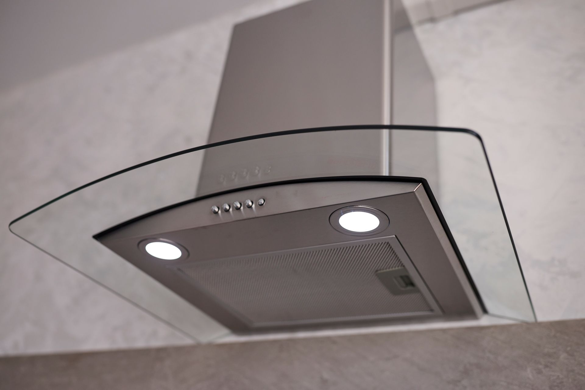 Stainless steel kitchen range hood with two lights mounted under a cabinet