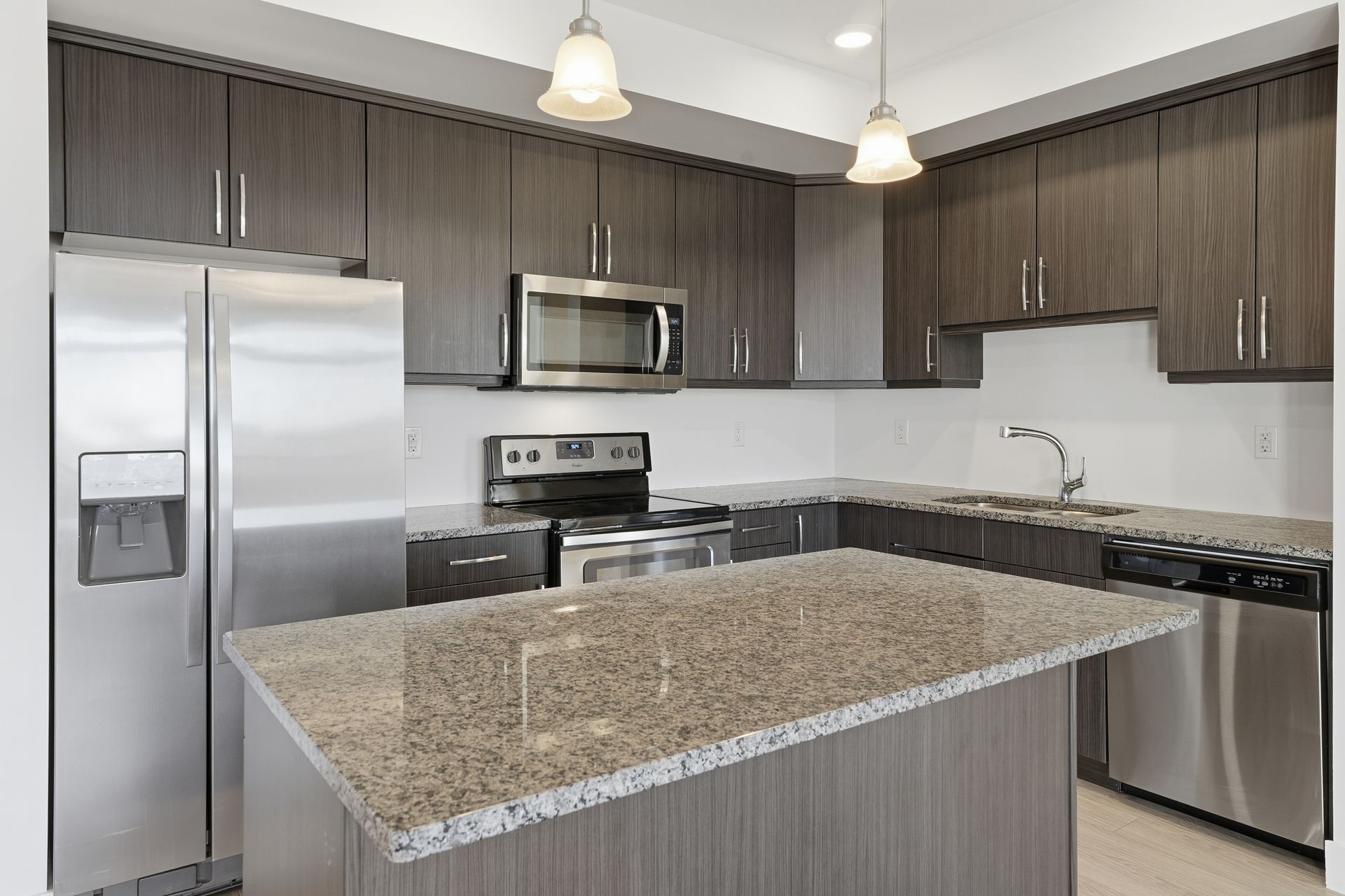Modern kitchen with granite island, stainless steel appliances, and wood cabinets