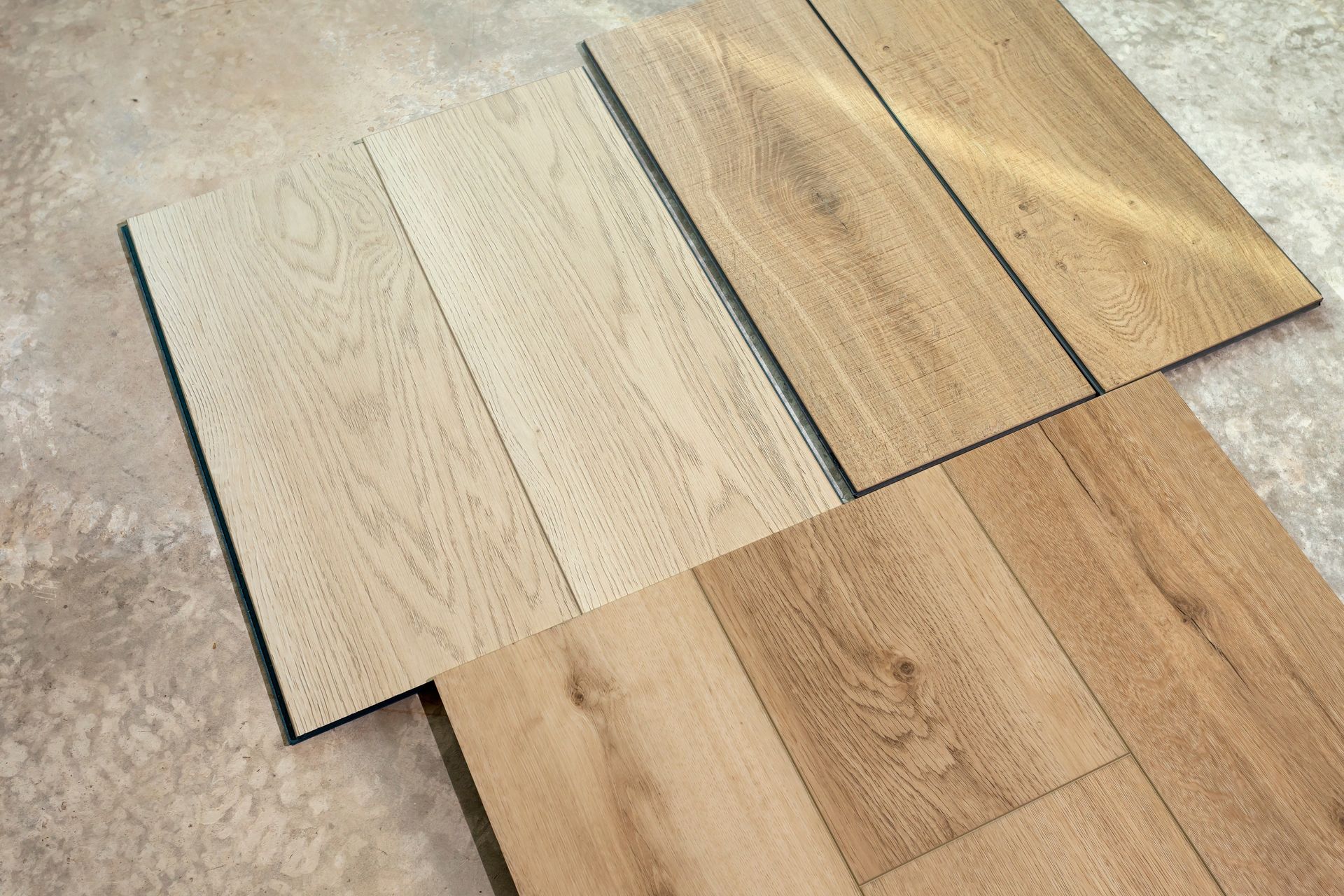 Light wood floor planks laid over a beige carpet, showing different wood tones and finishes