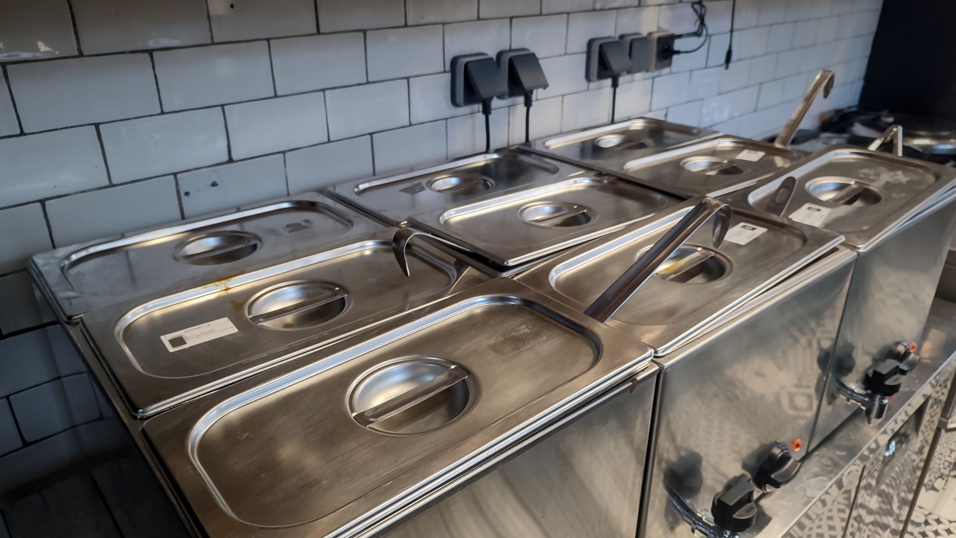 Stainless steel deep fryers with metal baskets in a tiled commercial kitchen, viewed from above