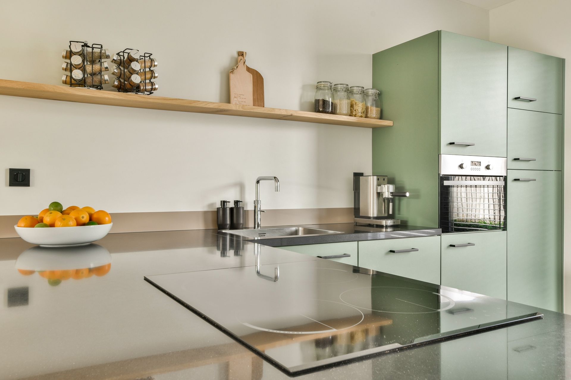 Modern kitchen with mint cabinets, stainless appliances, and a bowl of oranges on the counter