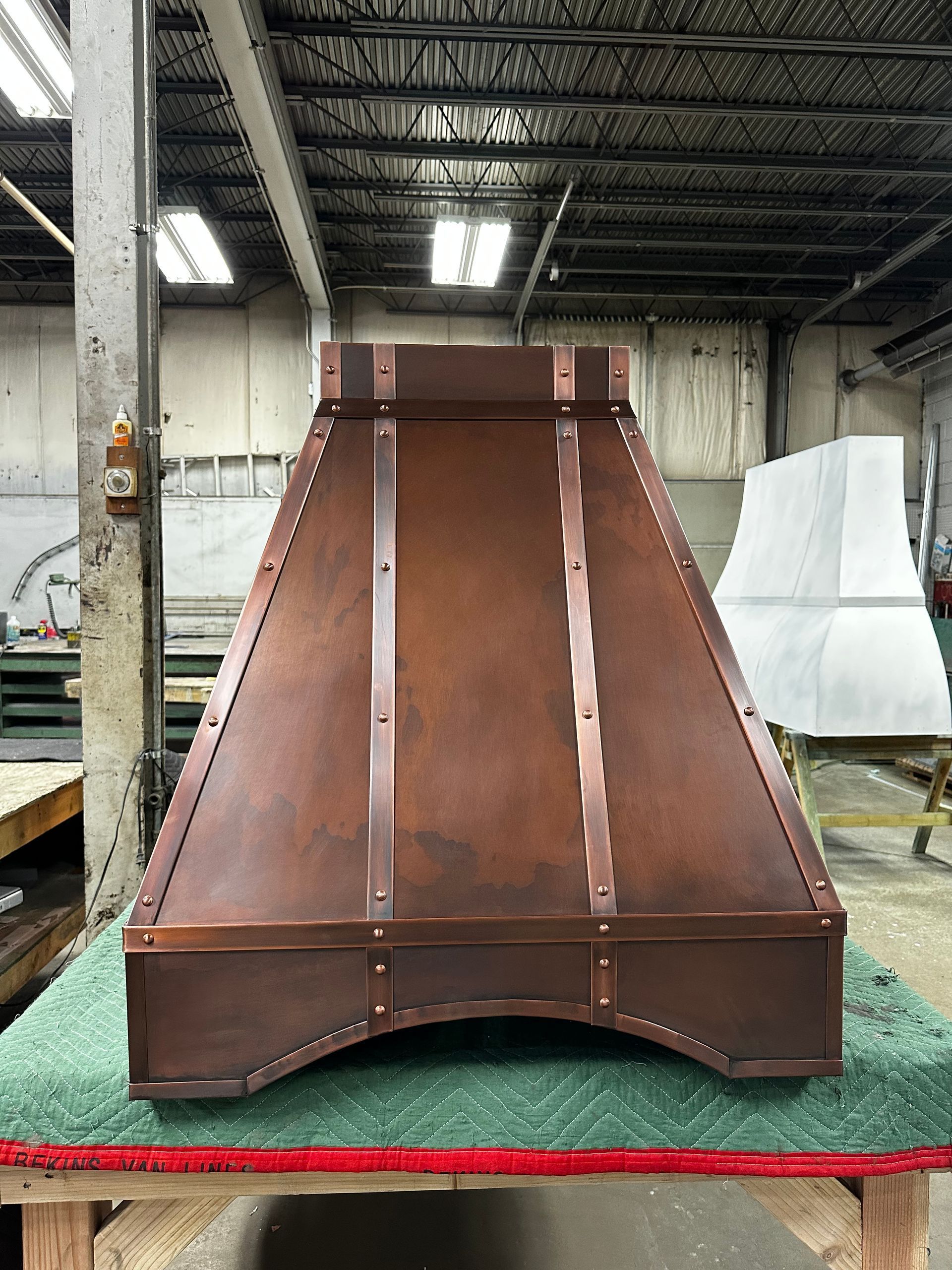 Rust-colored metal industrial hood or duct standing on a factory floor