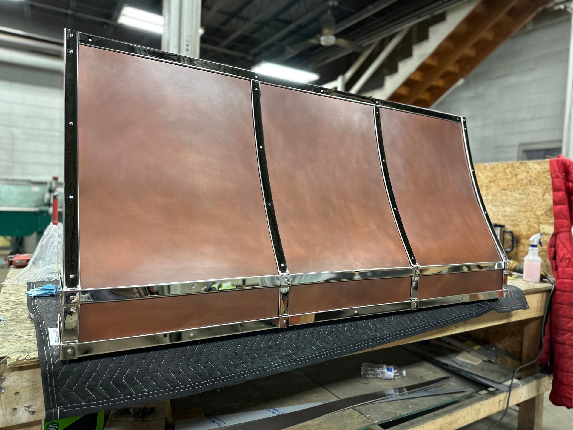 Copper-colored metal panels mounted on a black industrial frame in a workshop.