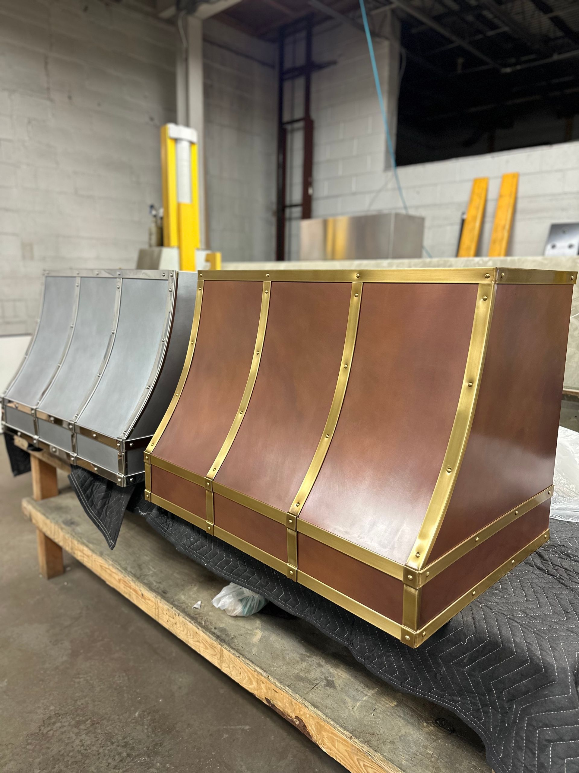 Industrial metal duct sections with gray and brown panels on a pallet in a warehouse