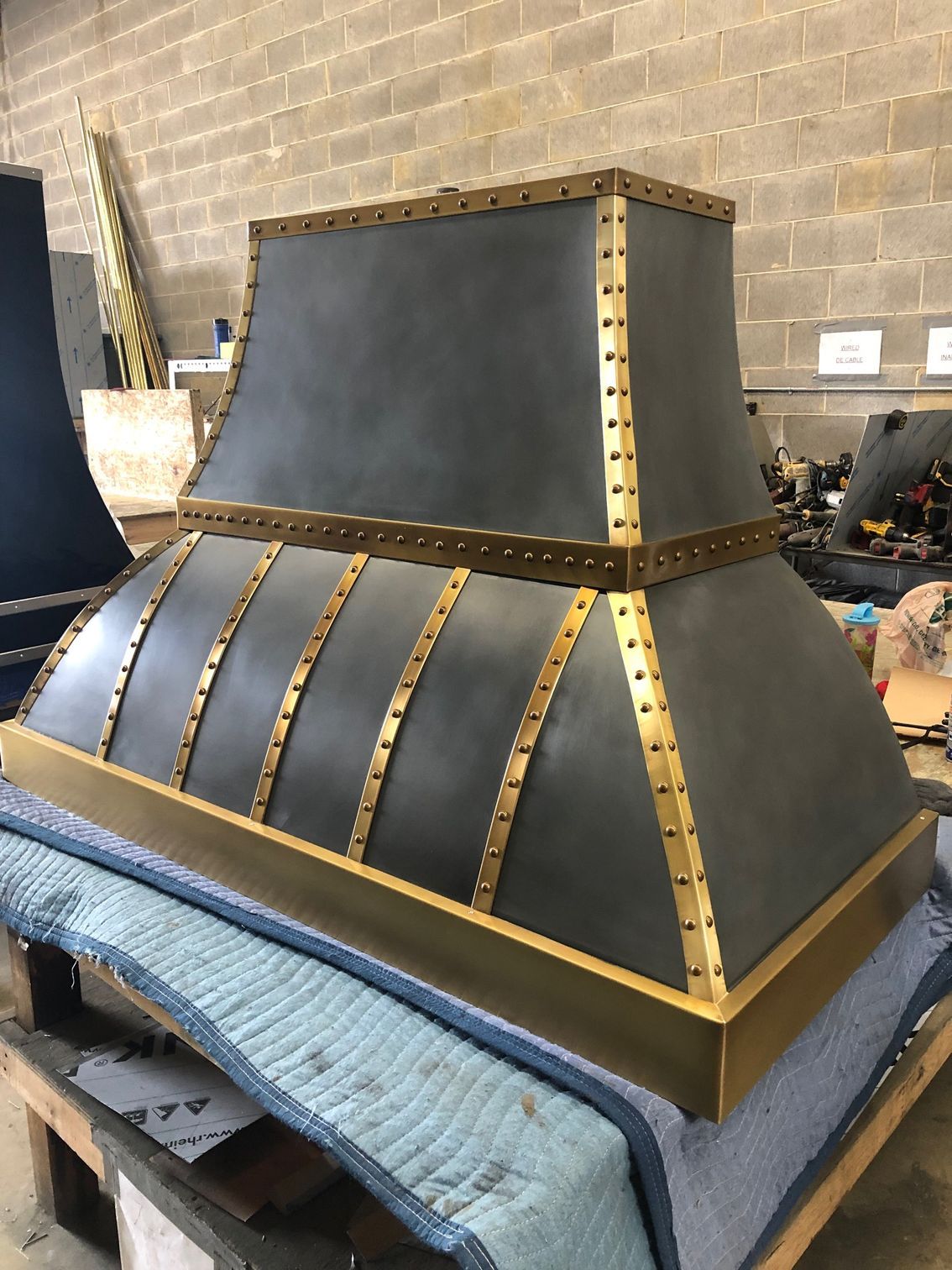Black and gold decorative hood or chimney cap on a workbench in a workshop