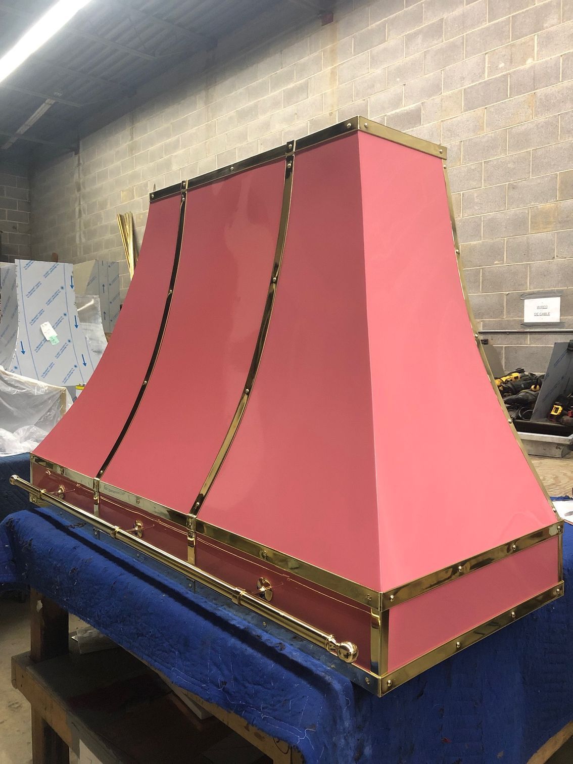 Pink and gold decorative model on a blue-covered table in a workshop-like room