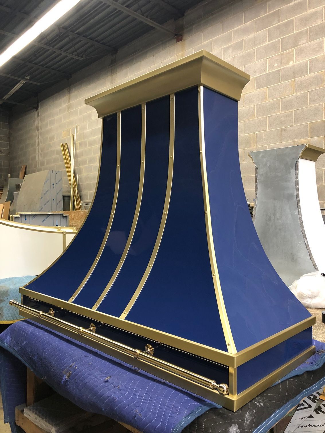 Blue and gold ornate decorative hood or chimney cover in a workshop with curved gold trim