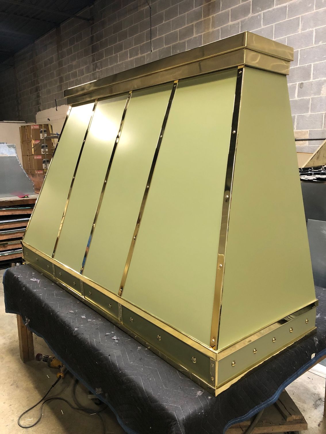 Gold metal rooftop vent hood on a black base in a workshop setting
