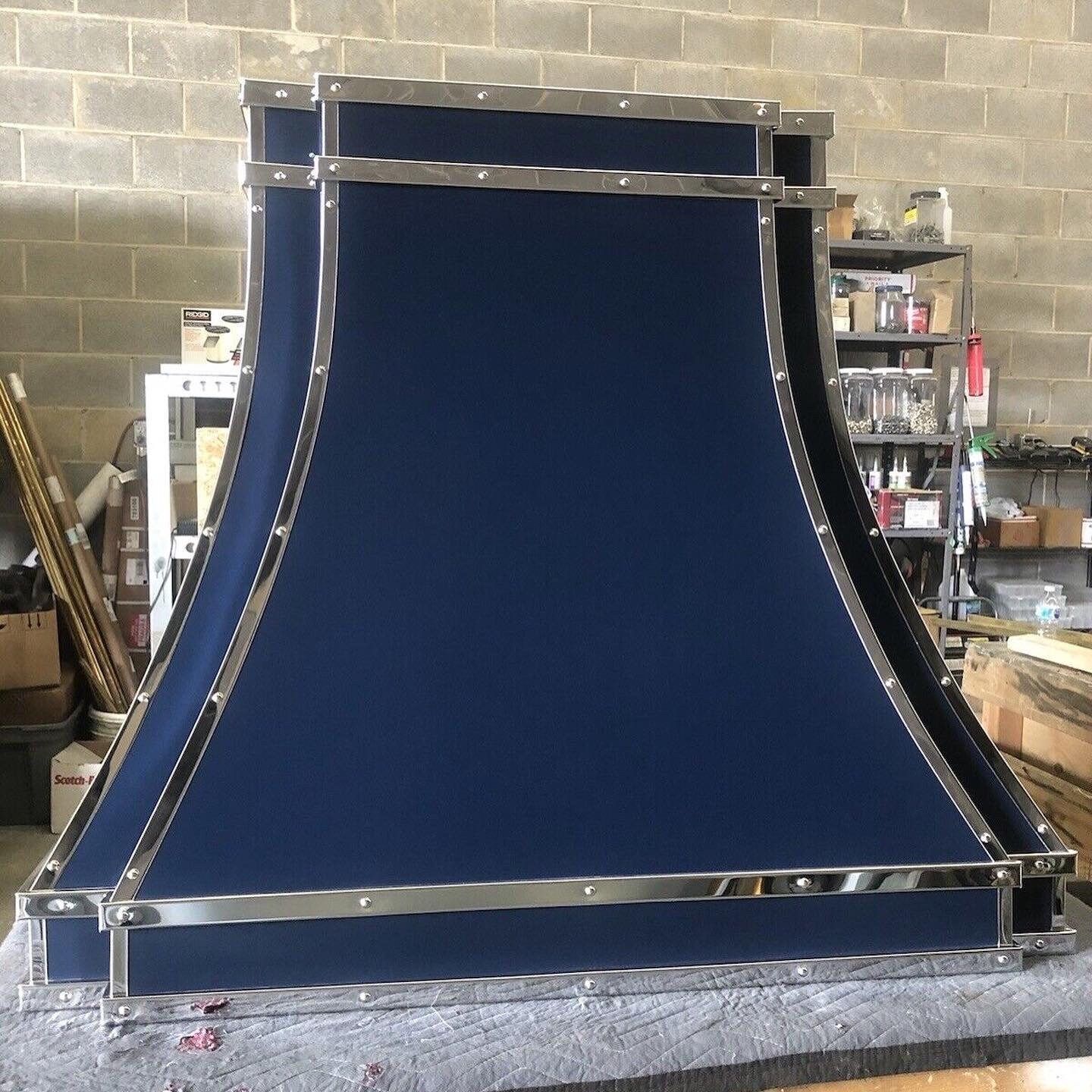 Large blue fabric and metal frame structure in a workshop, viewed from the front.